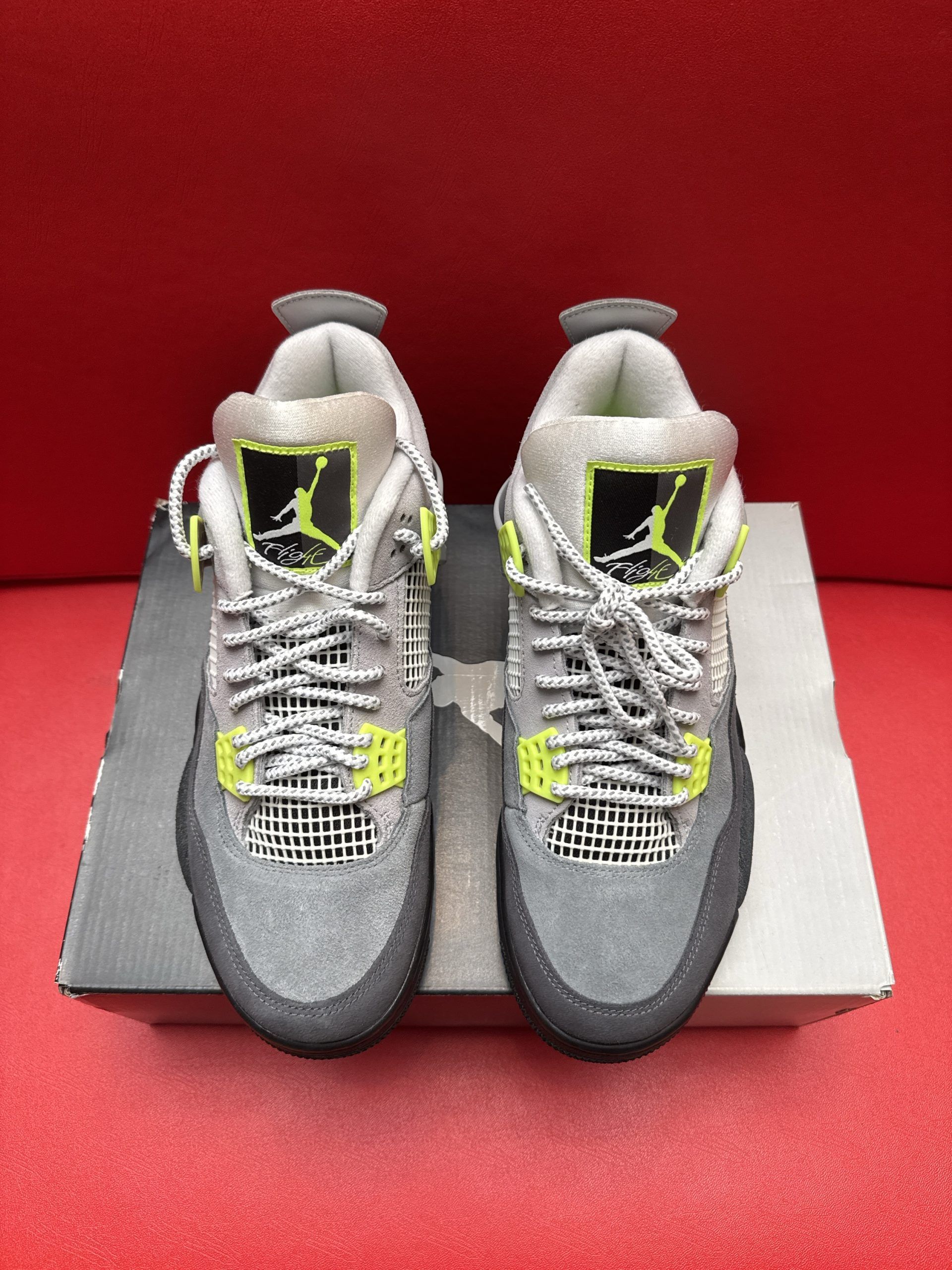 Gray and neon green Air Jordan 4 infant sneakers on a box, sole up.