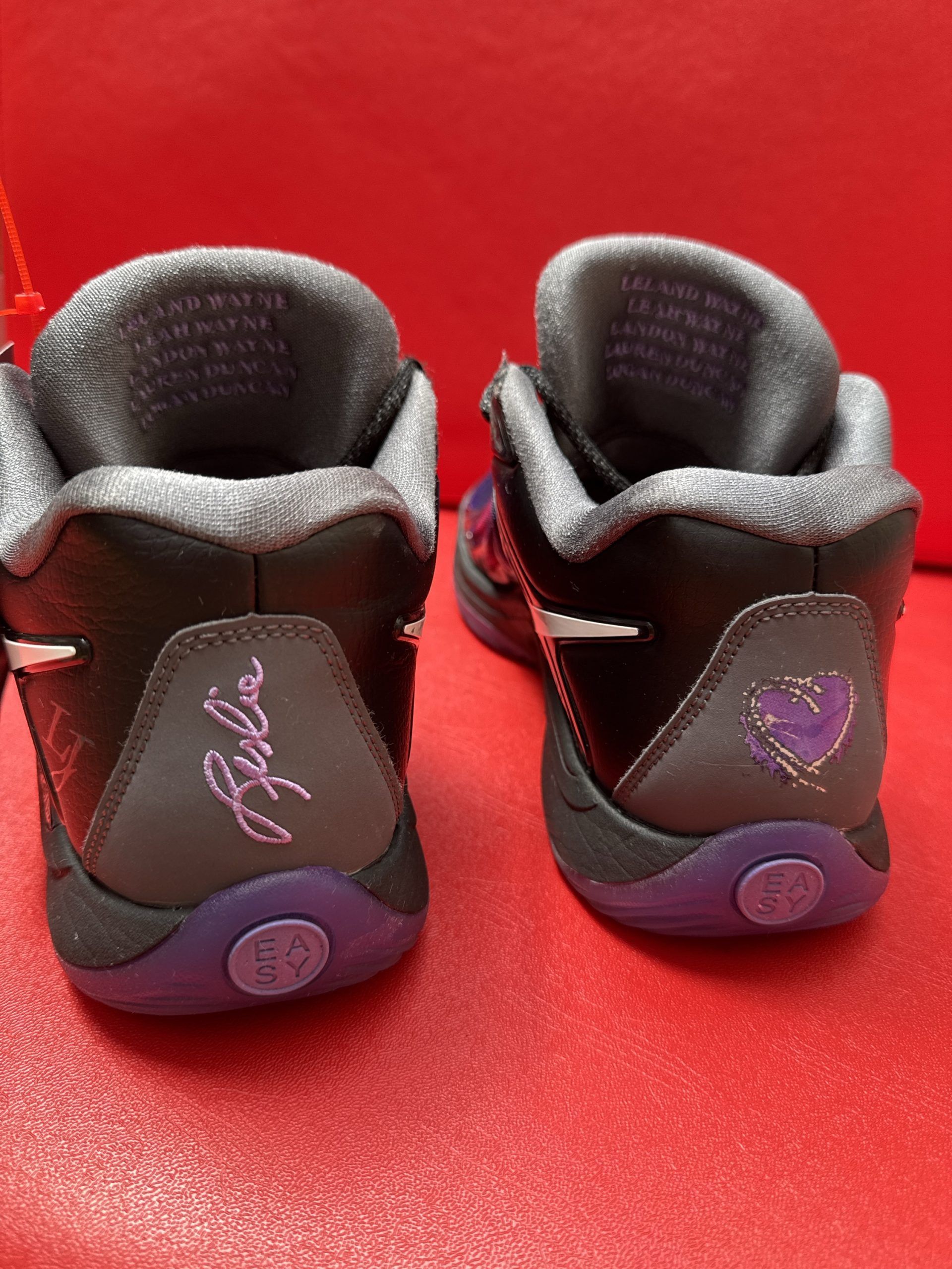 Black and purple Nike KD 10 basketball sneaker with a white swoosh, set on a red surface.