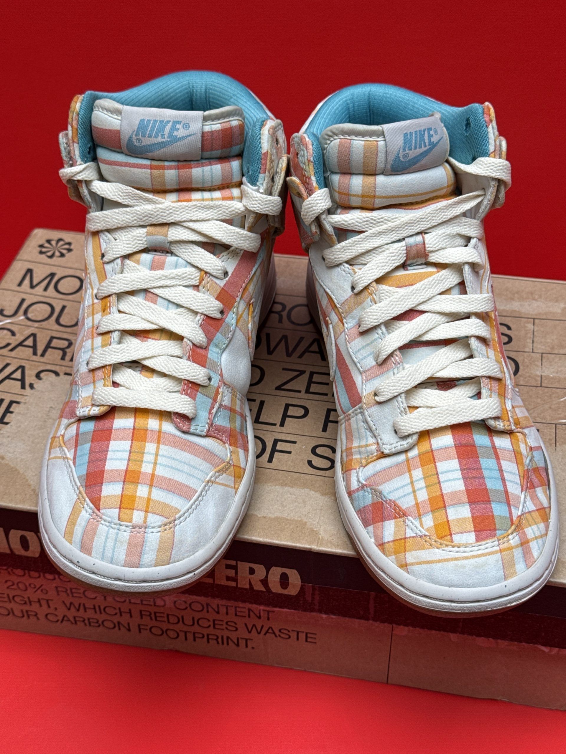 Nike high-top sneakers with a plaid pattern in orange, red, and blue on a box.