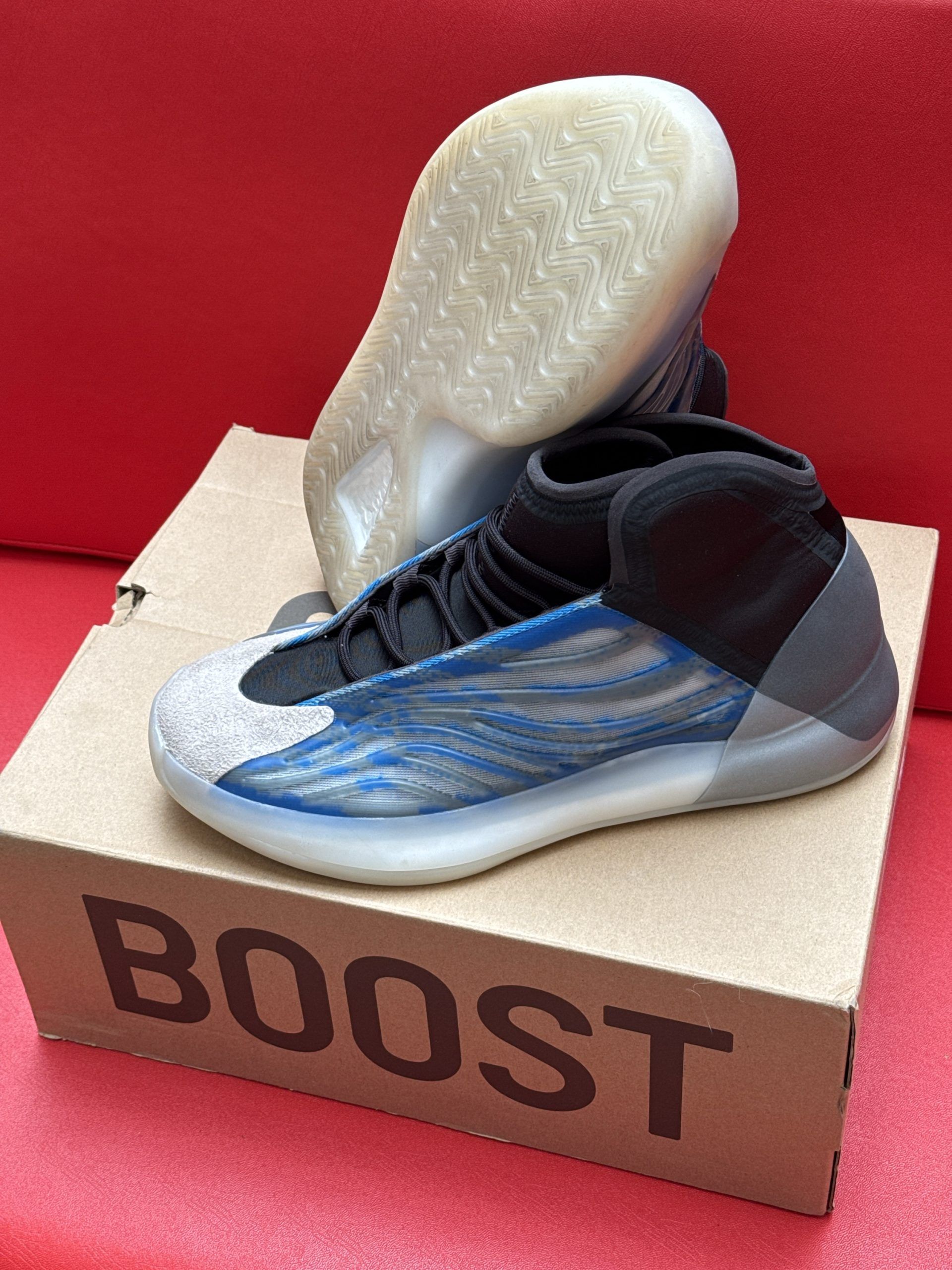 Yeezy basketball sneakers, blue and gray with a clear sole, on a cardboard box that reads 