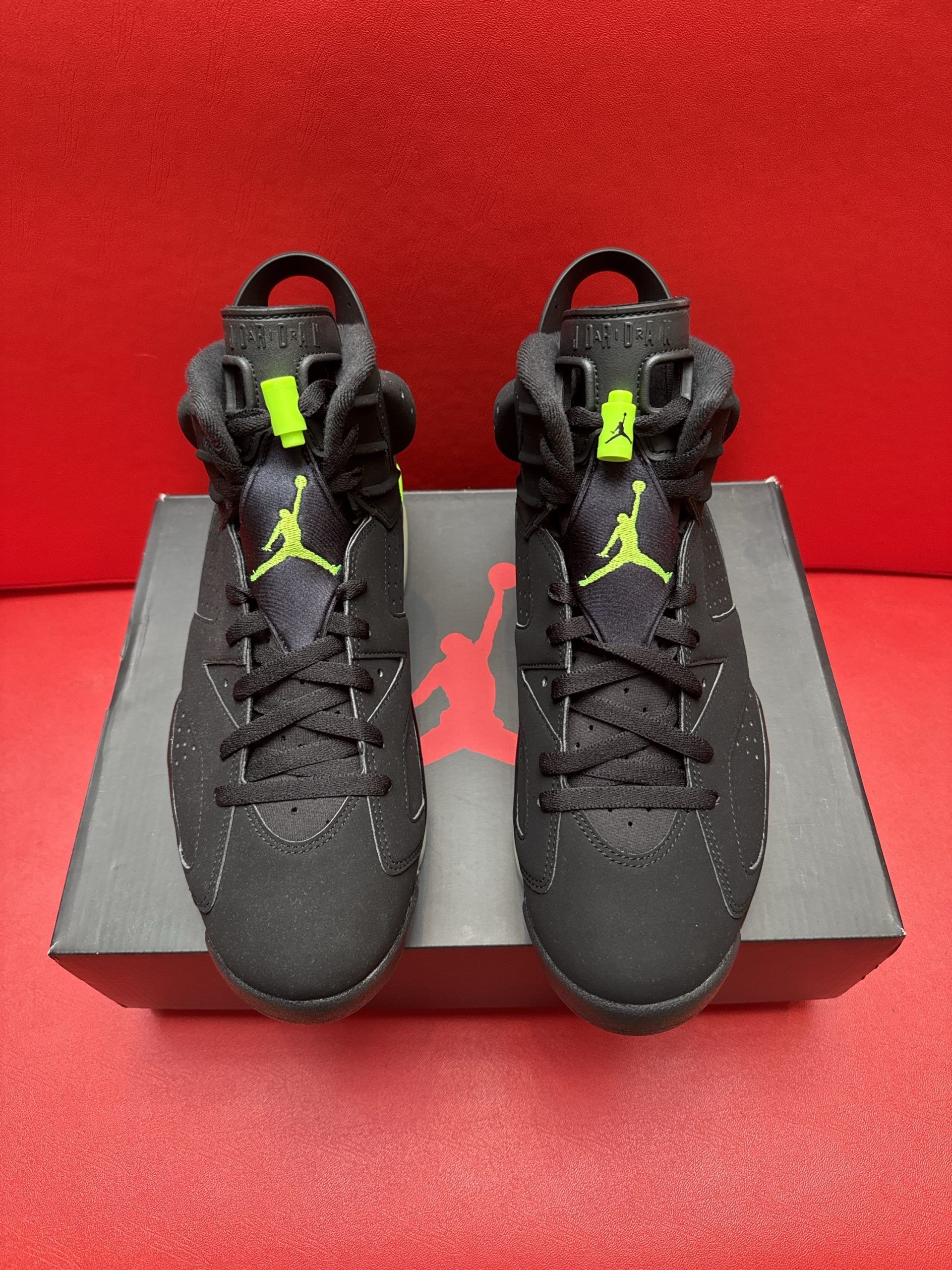 Black and green Air Jordan 6 sneakers on a box, with one sole facing up.