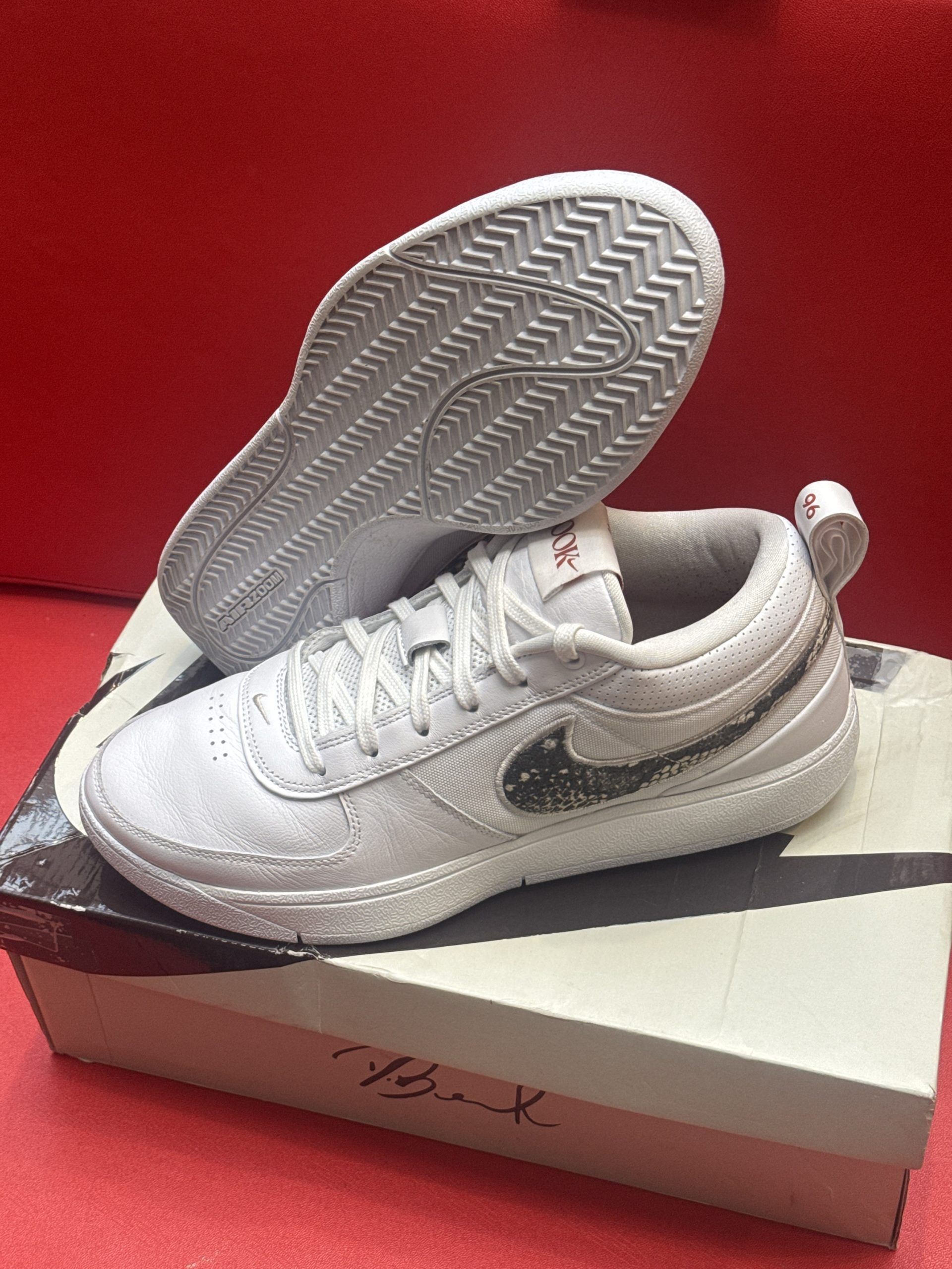 White Nike shoes on a shoebox, one shoe angled to show the sole.
