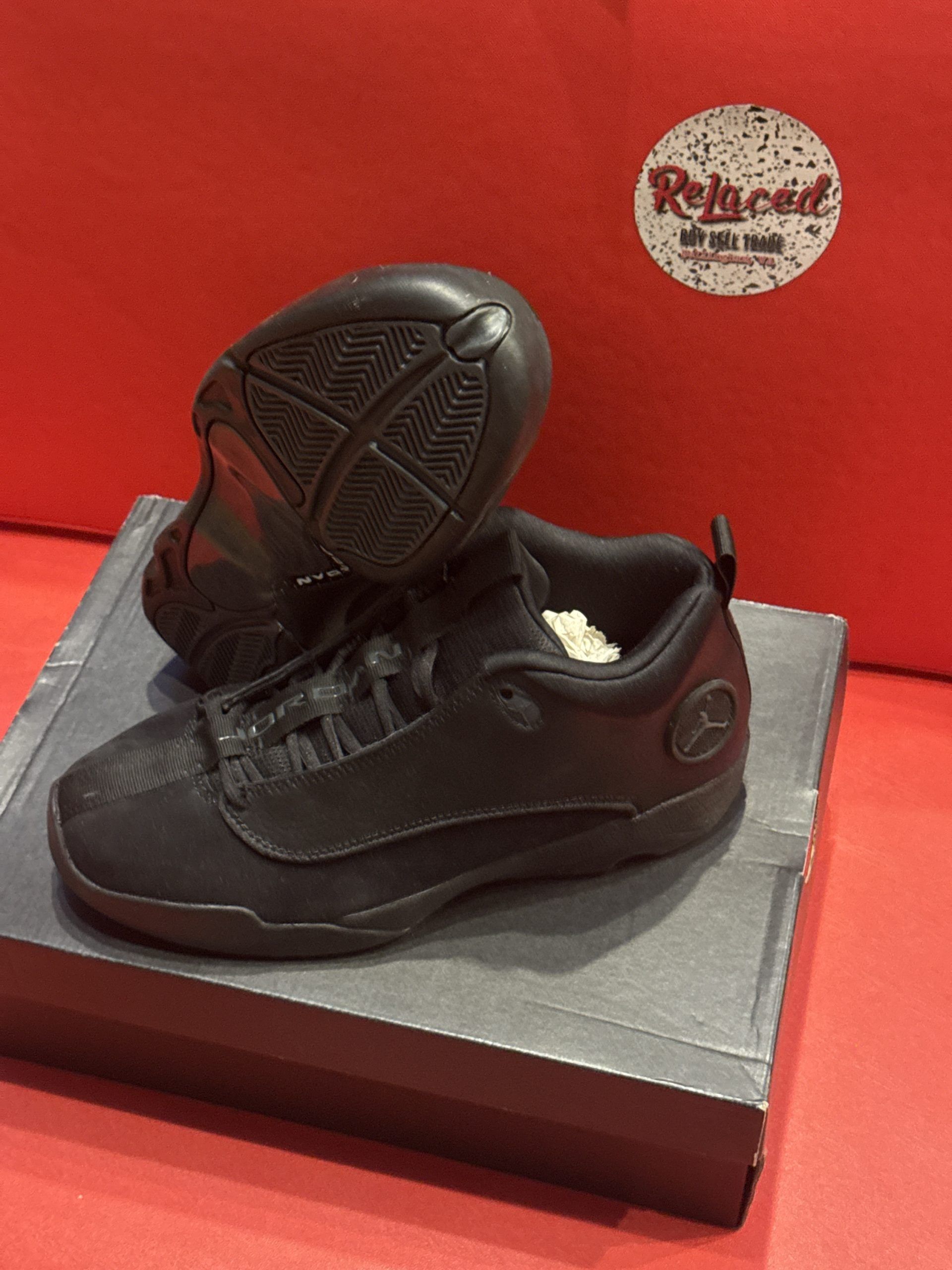 Black Jordan low-top sneakers on a shoebox. A red background is visible.