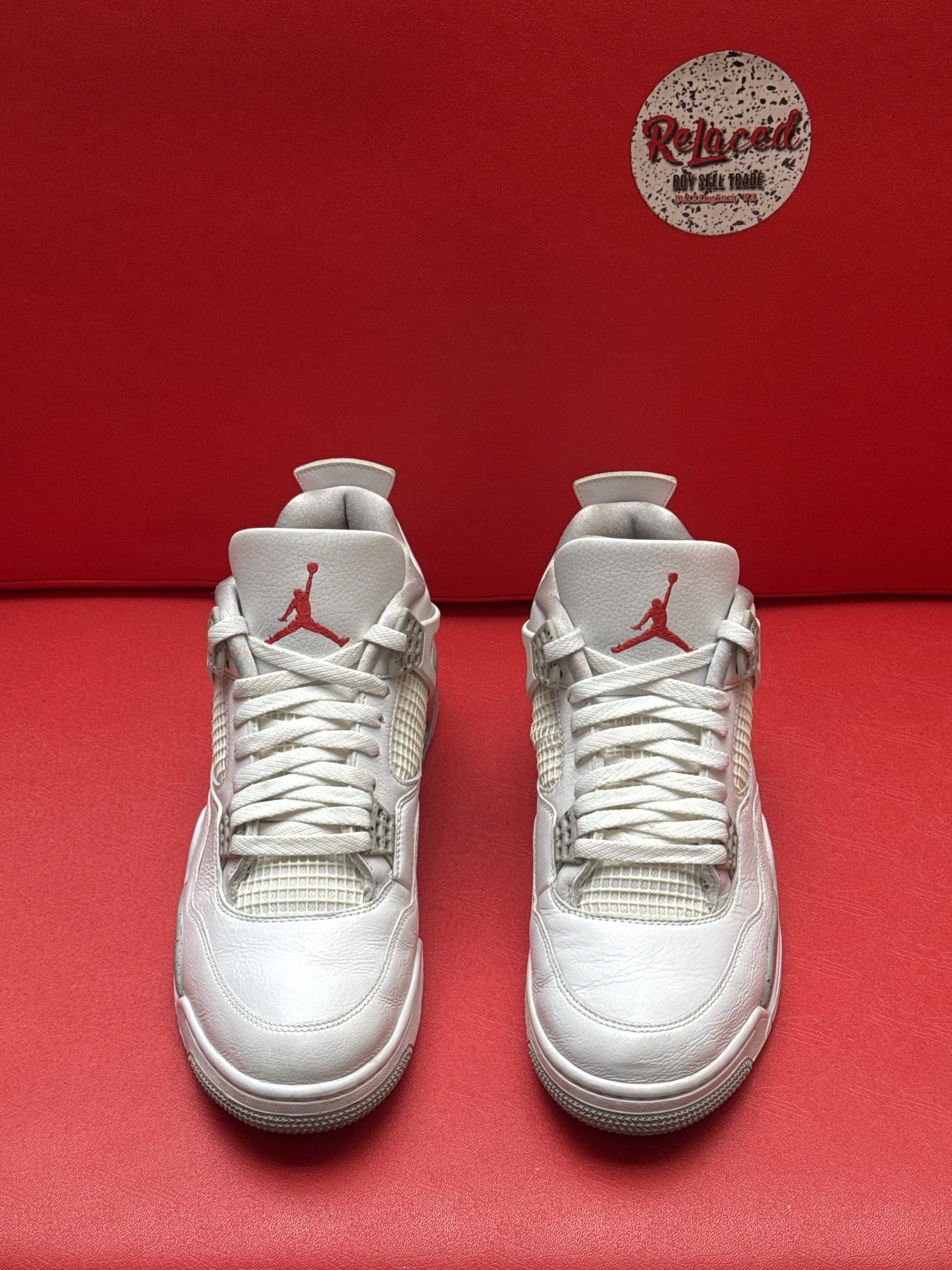 Air Jordan 4 sneakers, white and gray, red logo accents, on red background.