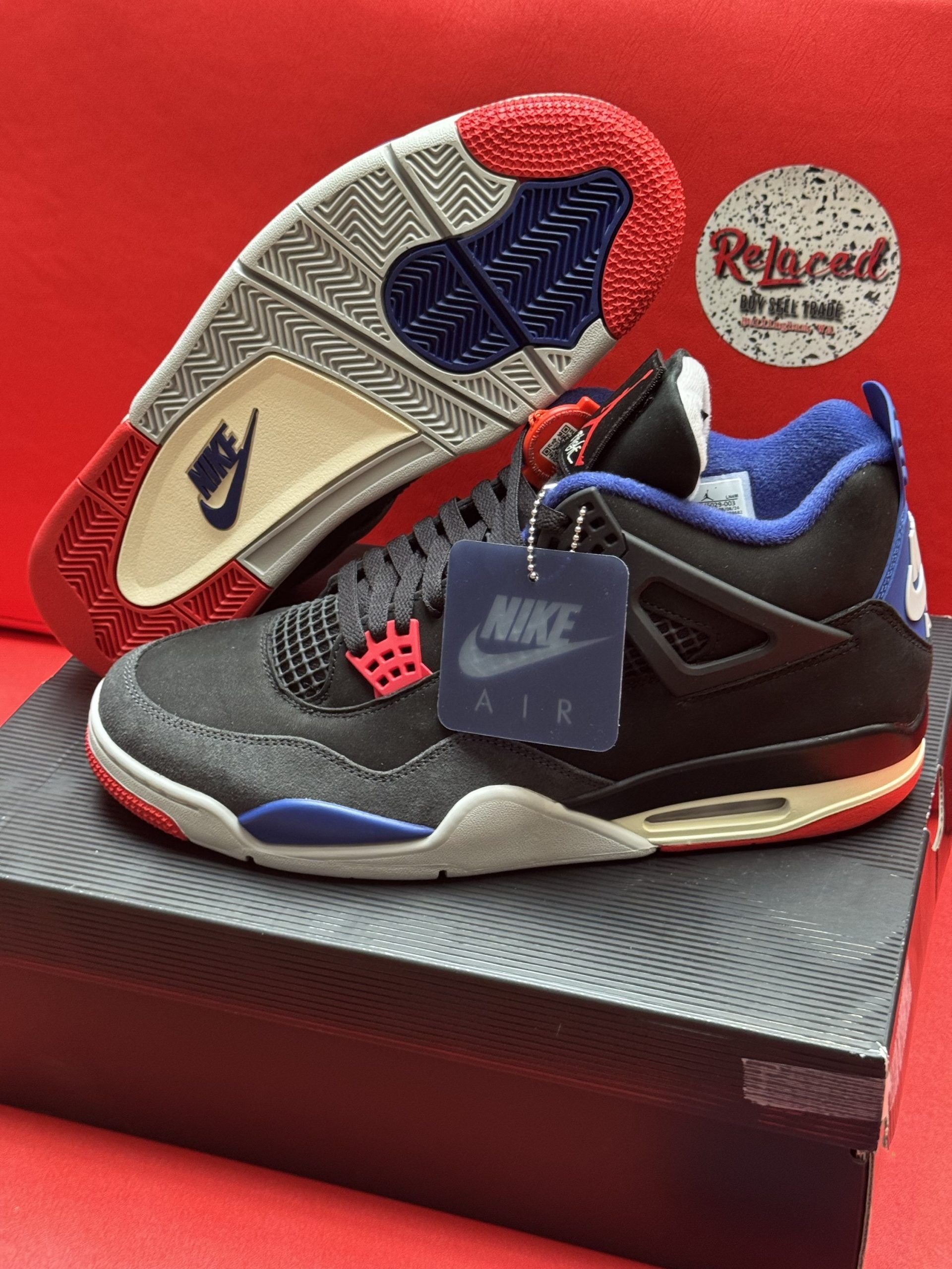 Black, red, and blue Air Jordan 4 sneaker with tag on top of a shoebox.
