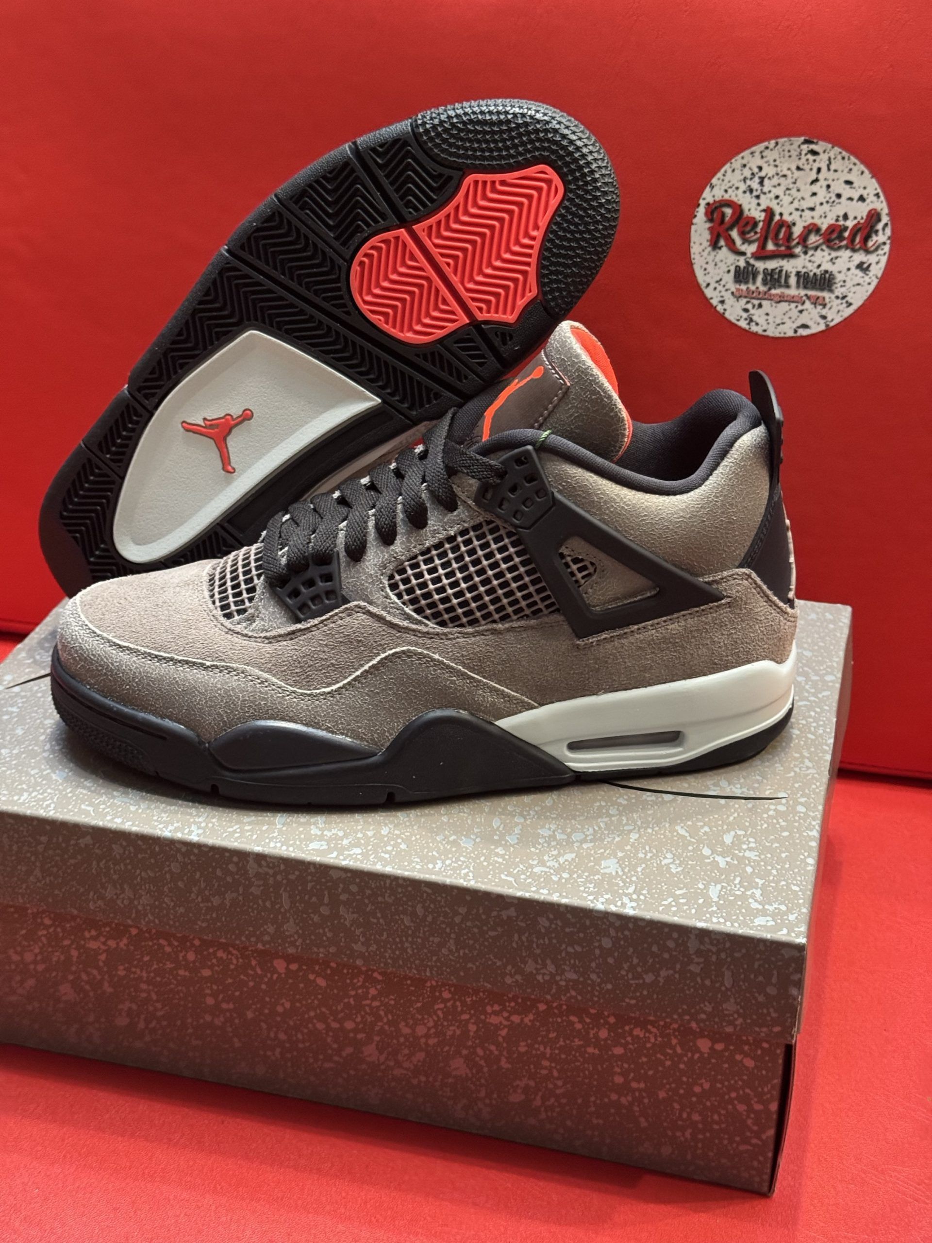 Air Jordan 4 sneakers, gray suede, black accents, sitting on a box, with the sole visible.