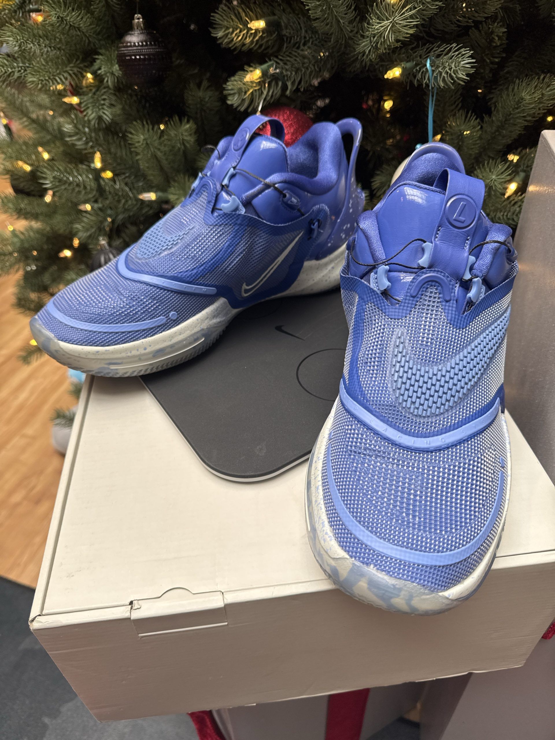 Blue and white Nike sneakers on a box, with a blurred Christmas tree background.