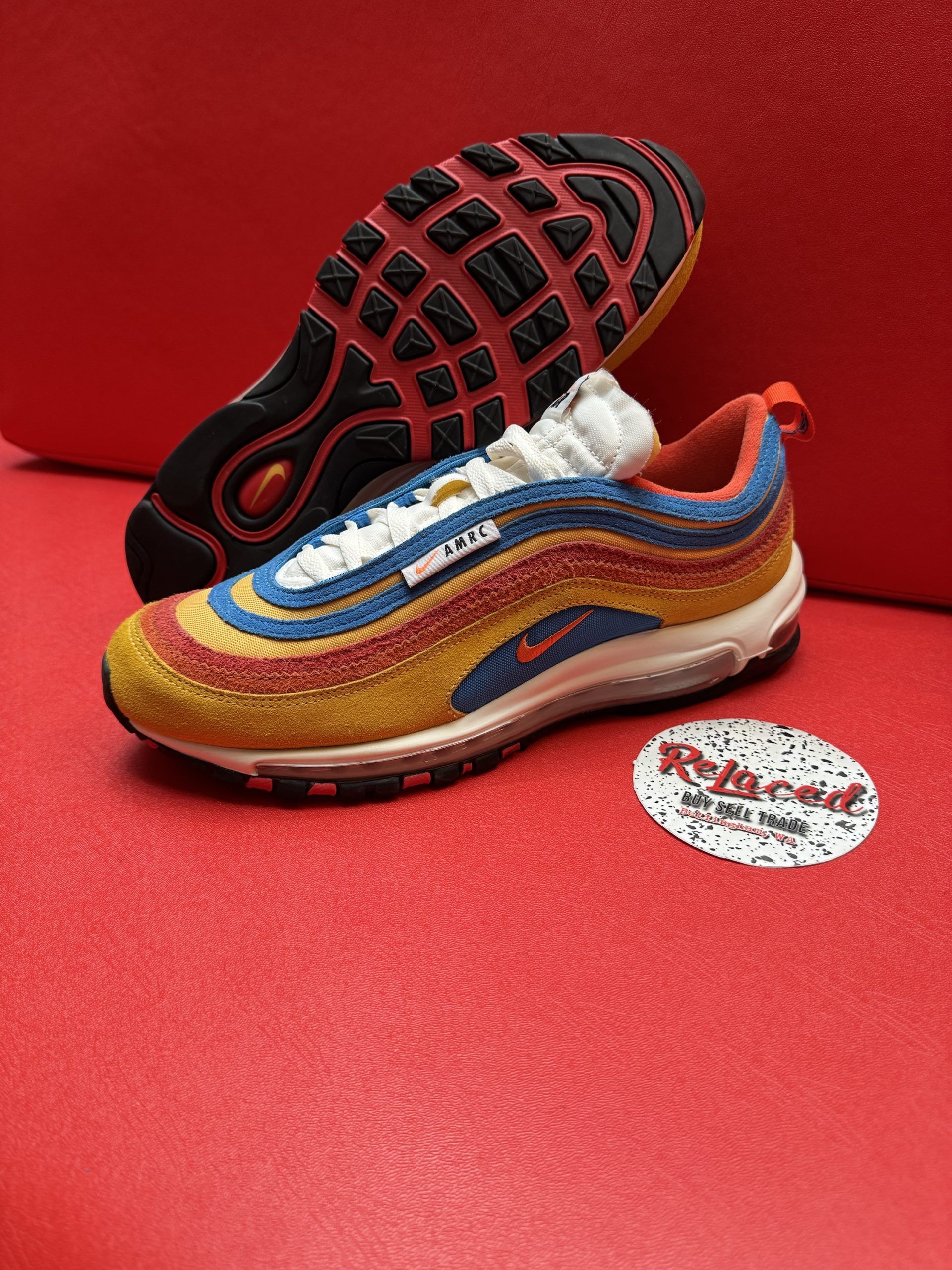 Colorful Nike Air Max 97 sneaker with visible sole, resting on a red surface.