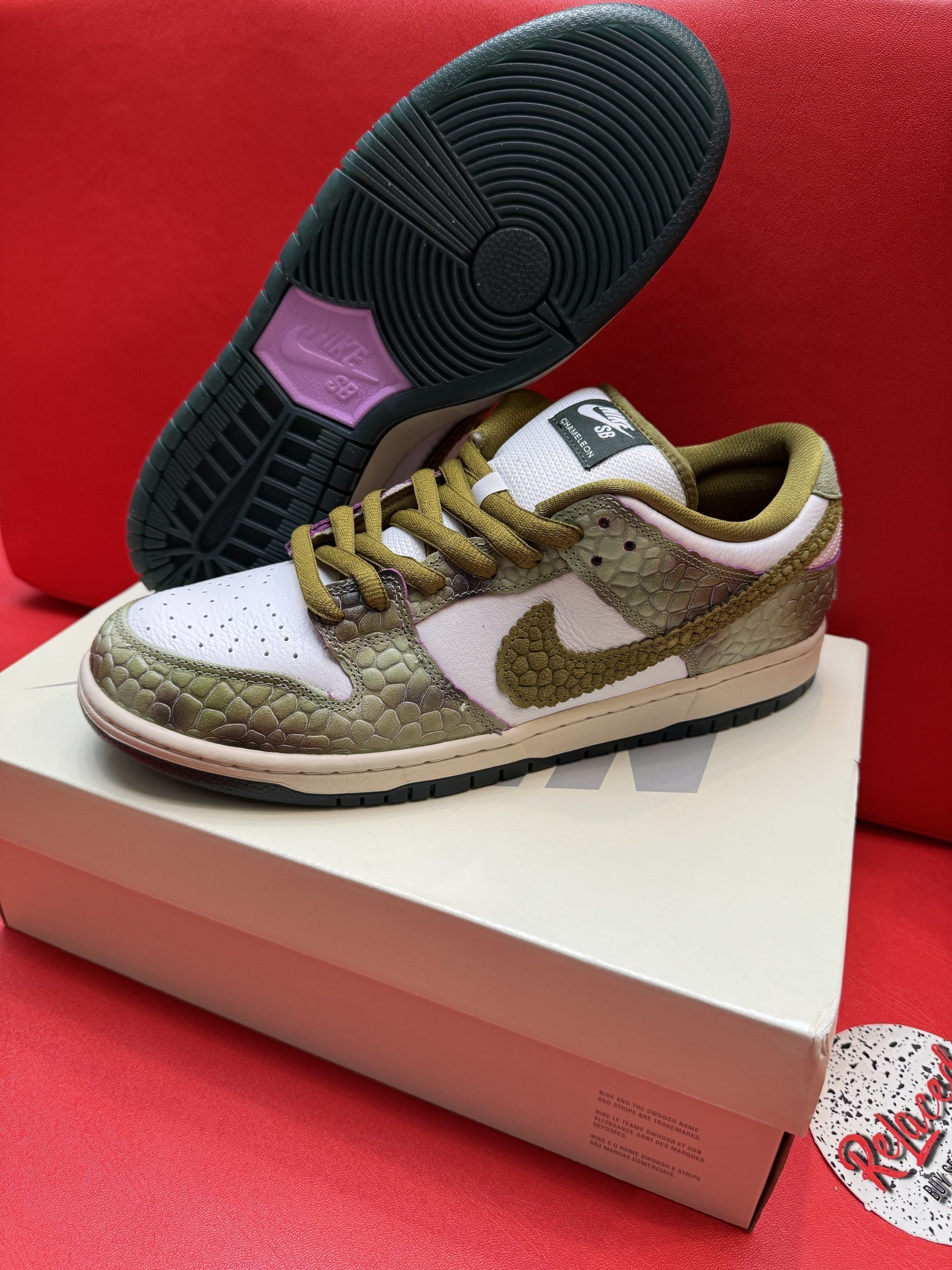 Nike Dunk Low sneakers, white and olive green, on top of a shoe box, sole visible.