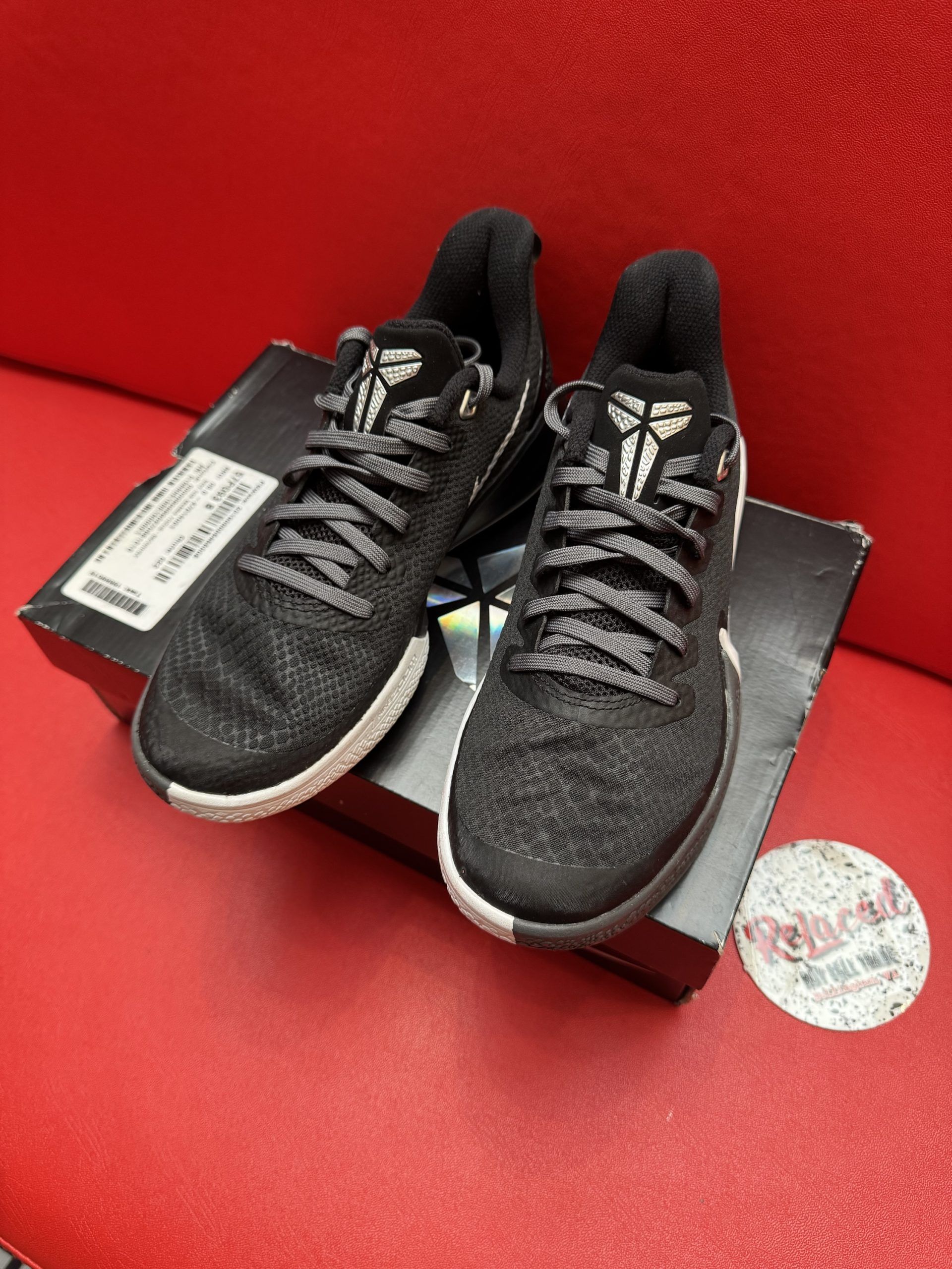 Black Nike sneakers with white swoosh, on a box, with sole visible.