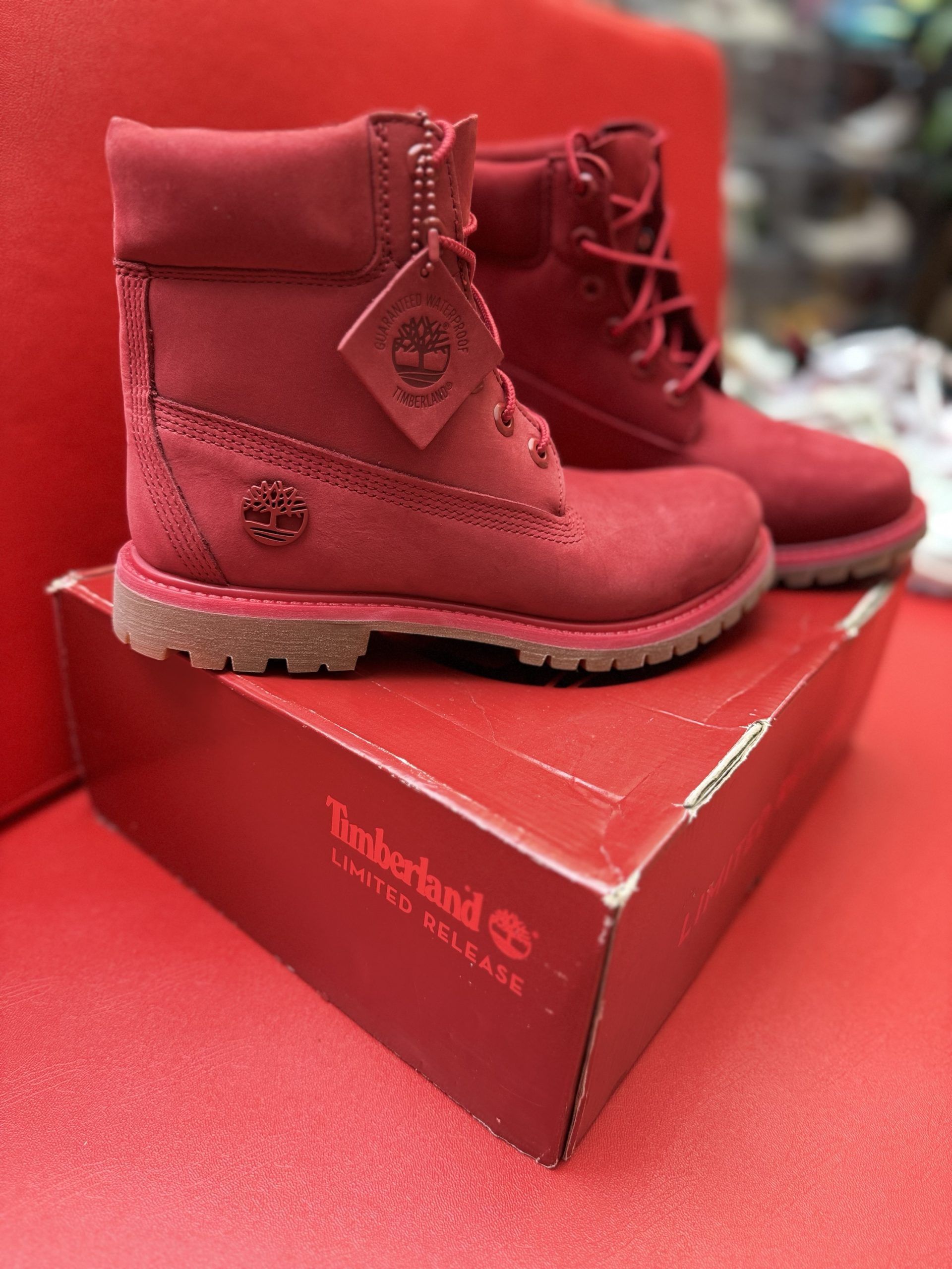 Red Timberland boots with the box on a red surface.