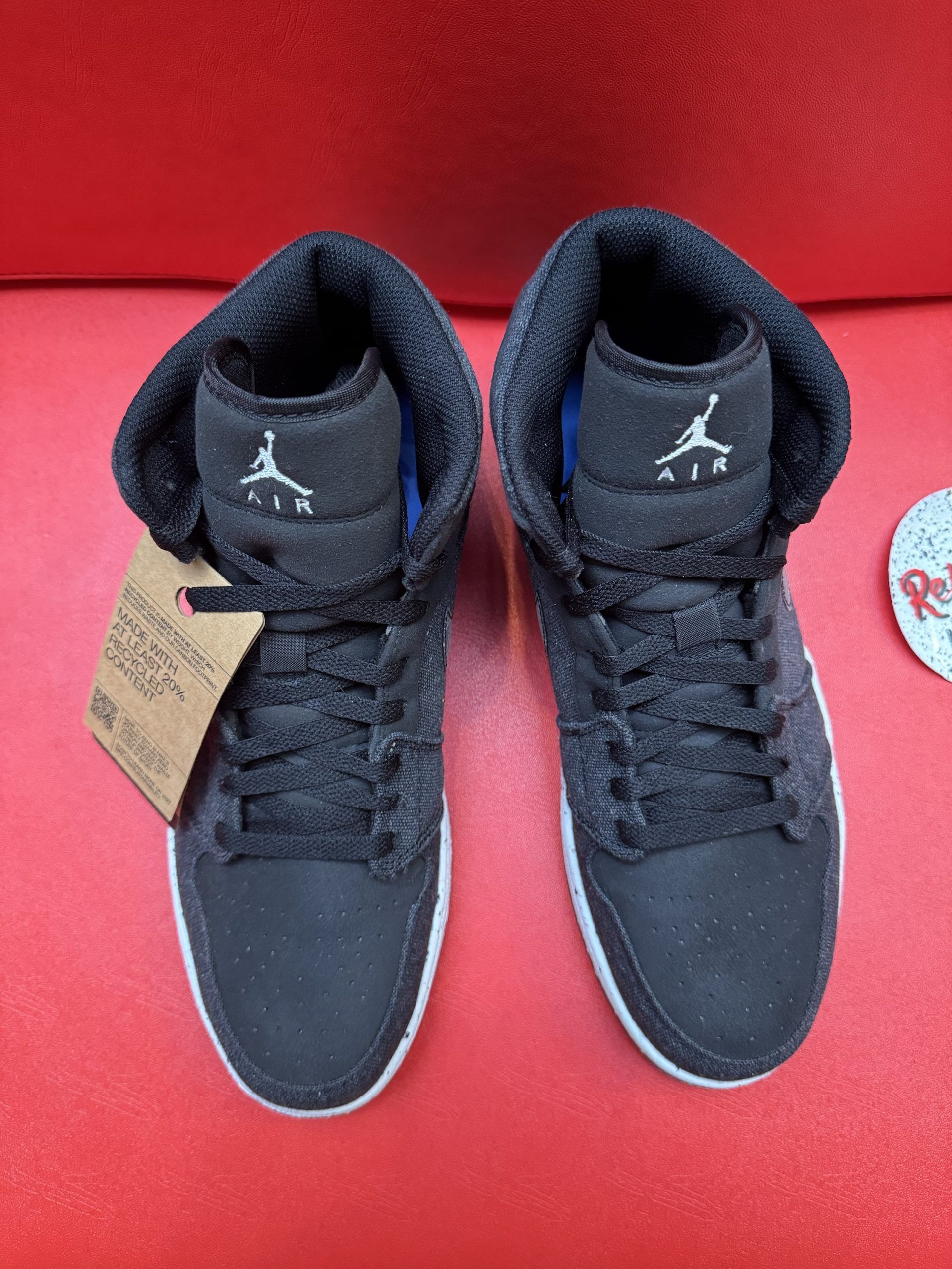 Black Nike Air Jordan sneaker with speckled sole on a red surface.