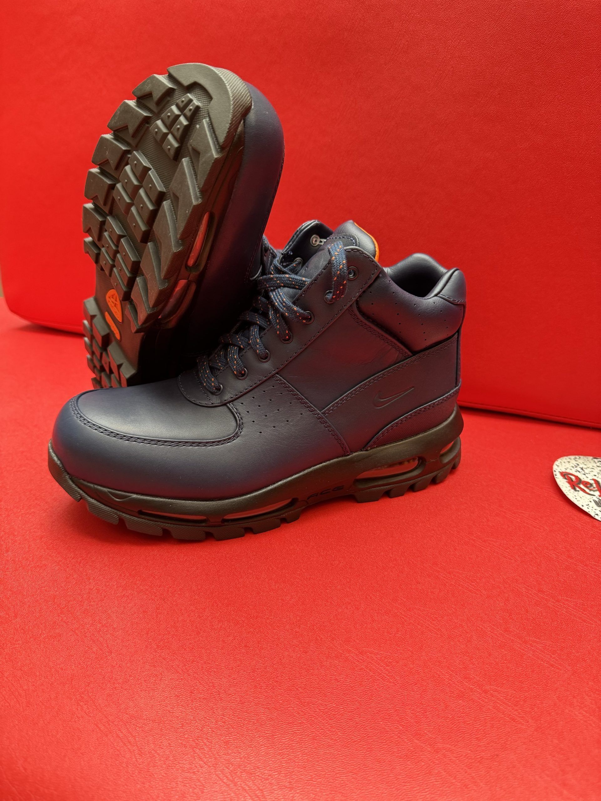Navy blue work boots with thick black soles on a red surface.