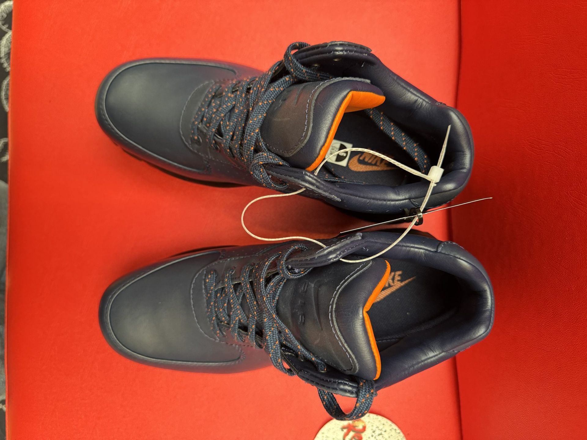 Navy blue work boots with thick black soles on a red surface.