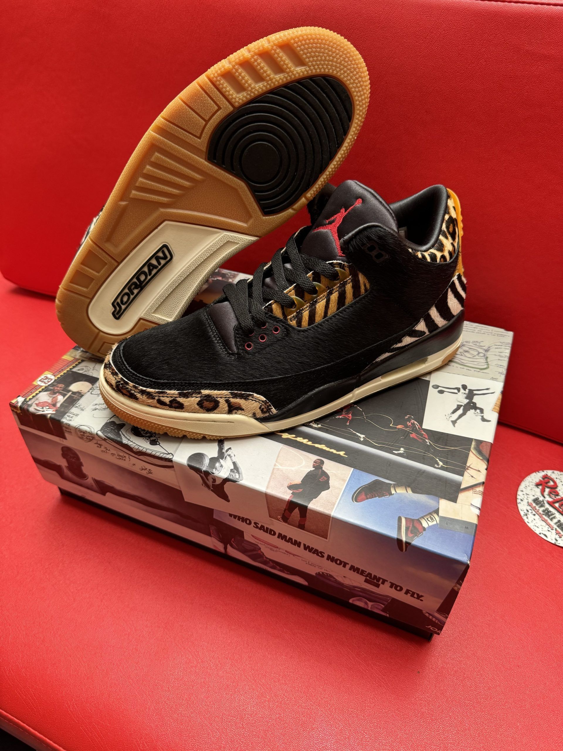 Black and animal print Air Jordan 3 sneakers on a box, with a gum sole in view.