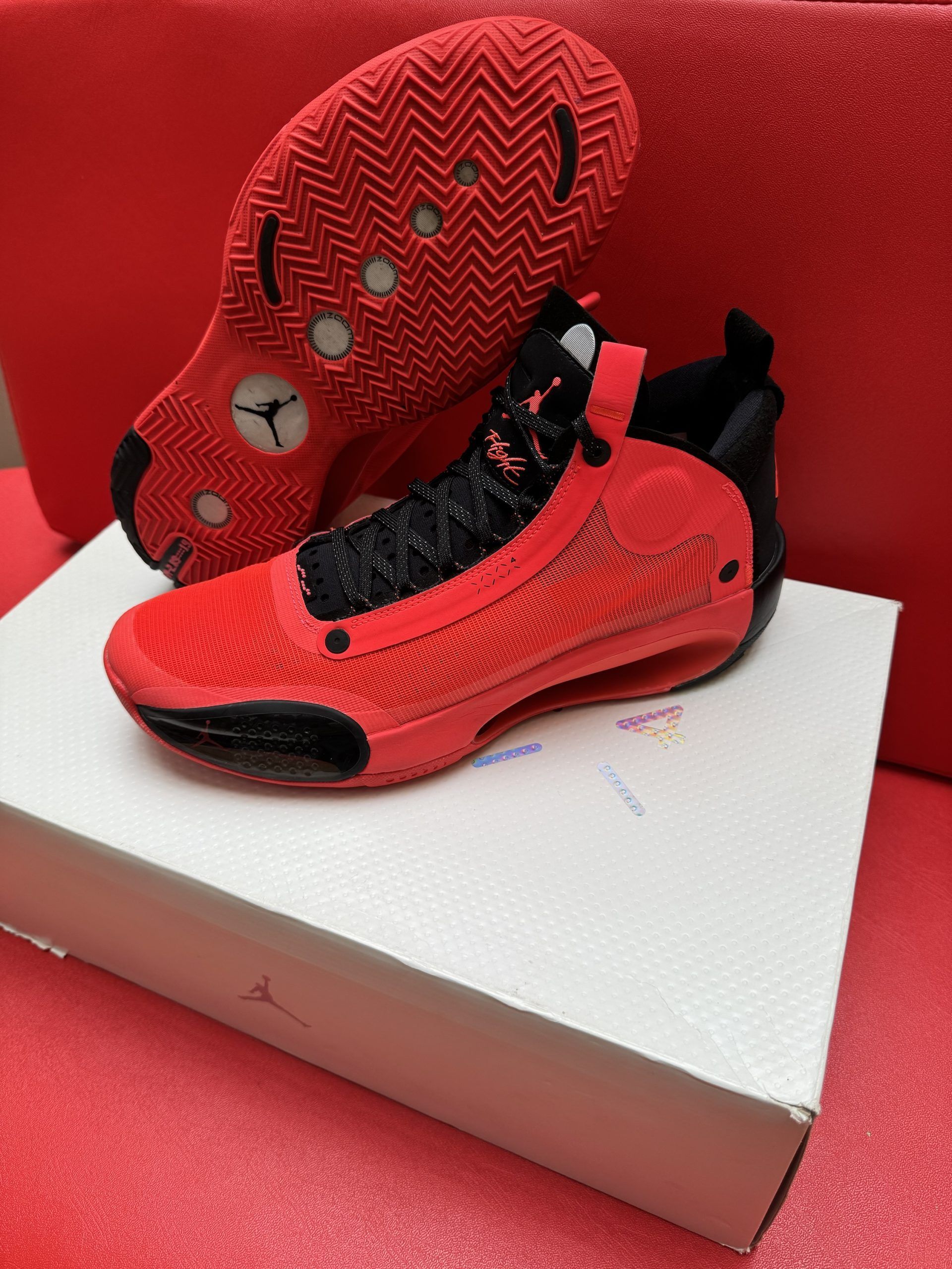 Red and black Air Jordan basketball shoes on a white box and a red surface.