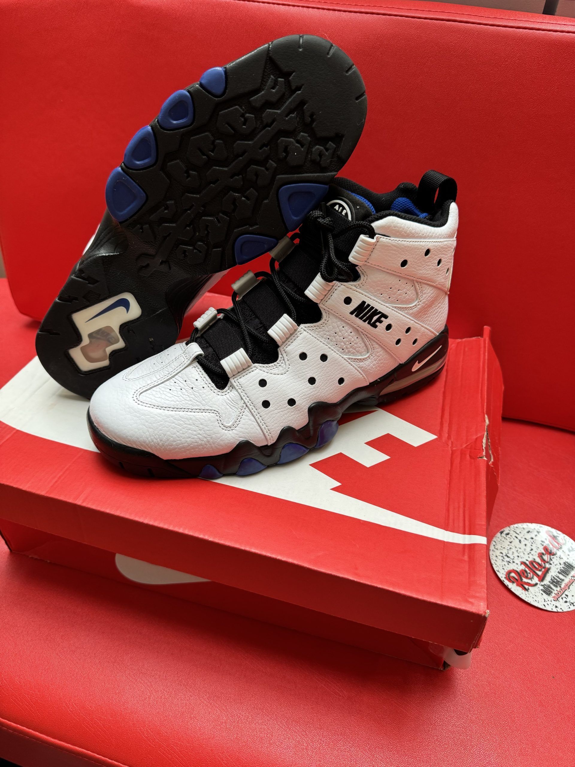 White and black Nike Barkley basketball sneaker with blue accents on a Nike box.