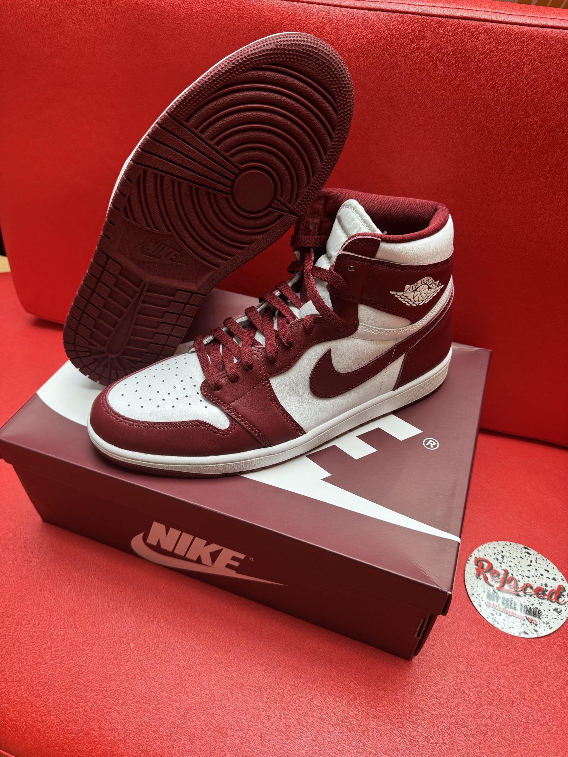 Air Jordan 1 sneakers in burgundy and white on top of a Nike shoe box.