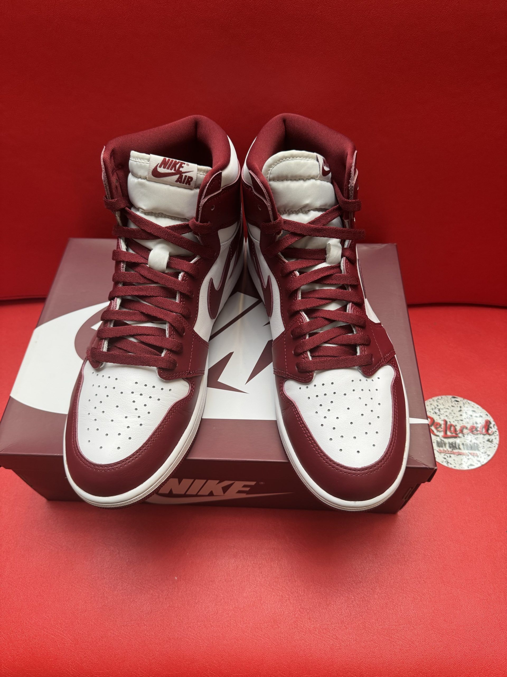 Air Jordan 1 sneakers in burgundy and white on top of a Nike shoe box.