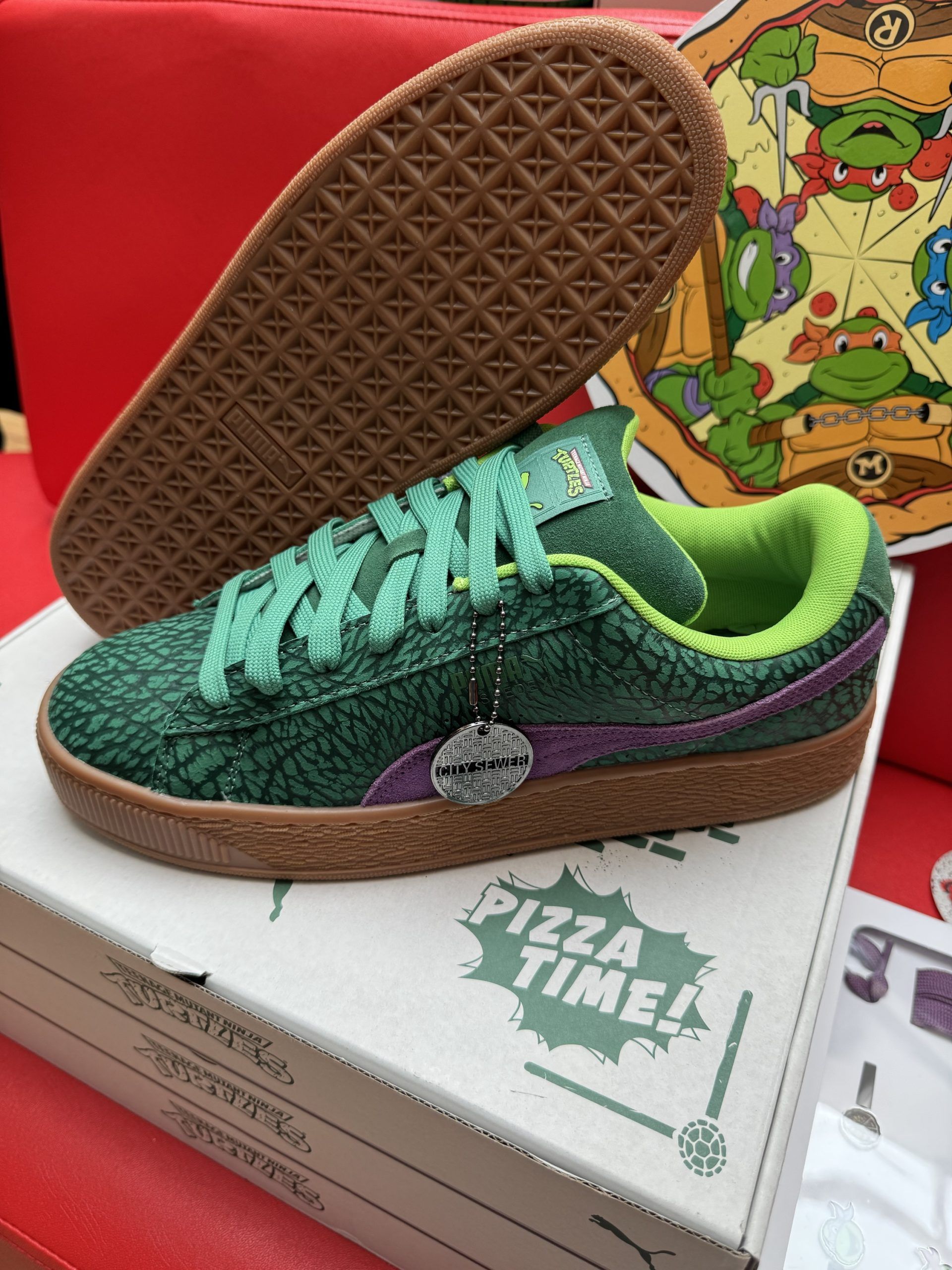 Green and purple Puma sneakers with Teenage Mutant Ninja Turtles theme, on pizza box.