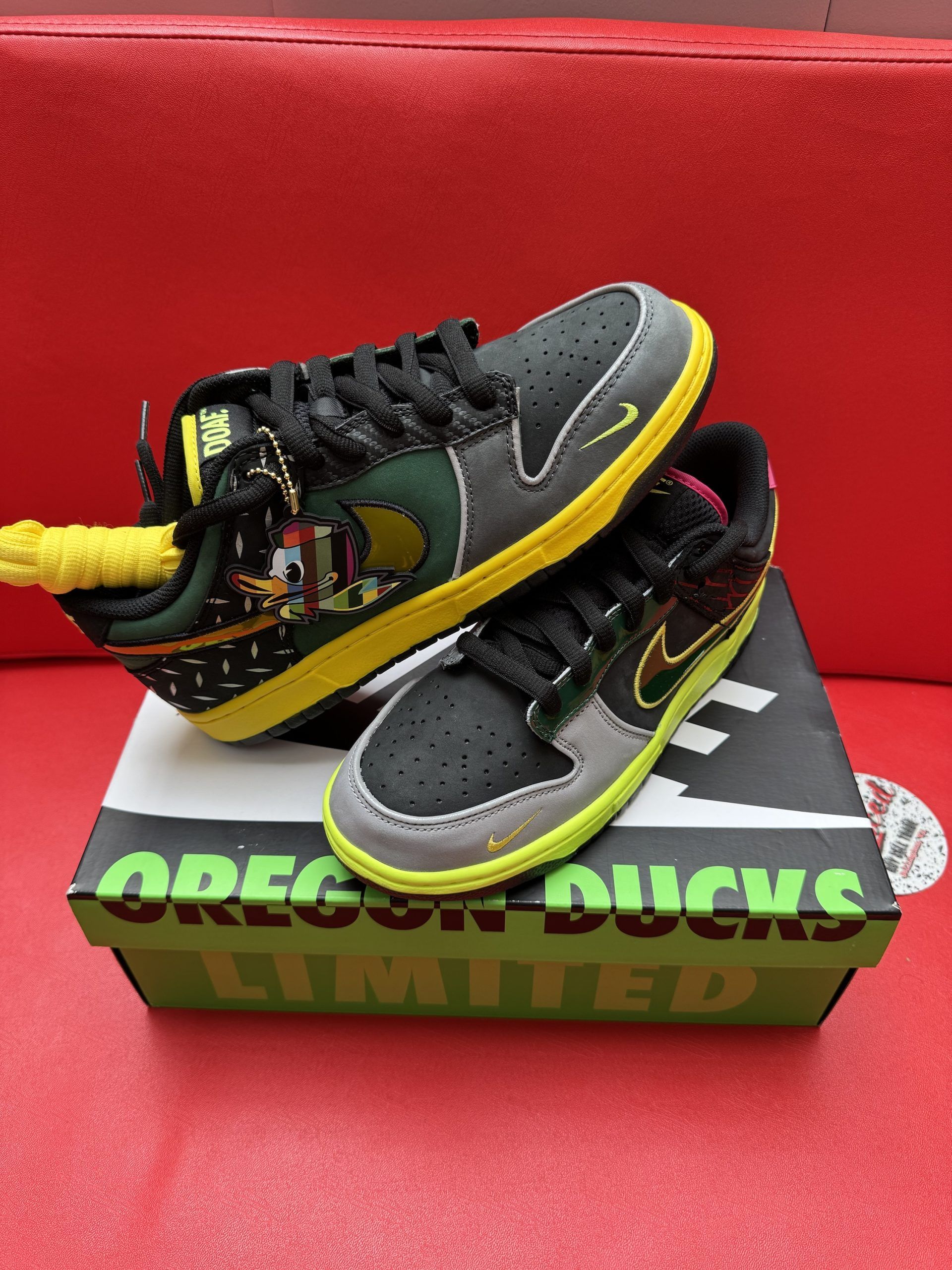 Black, green, and pink Nike Dunk Low Oregon Ducks sneakers on a matching box.