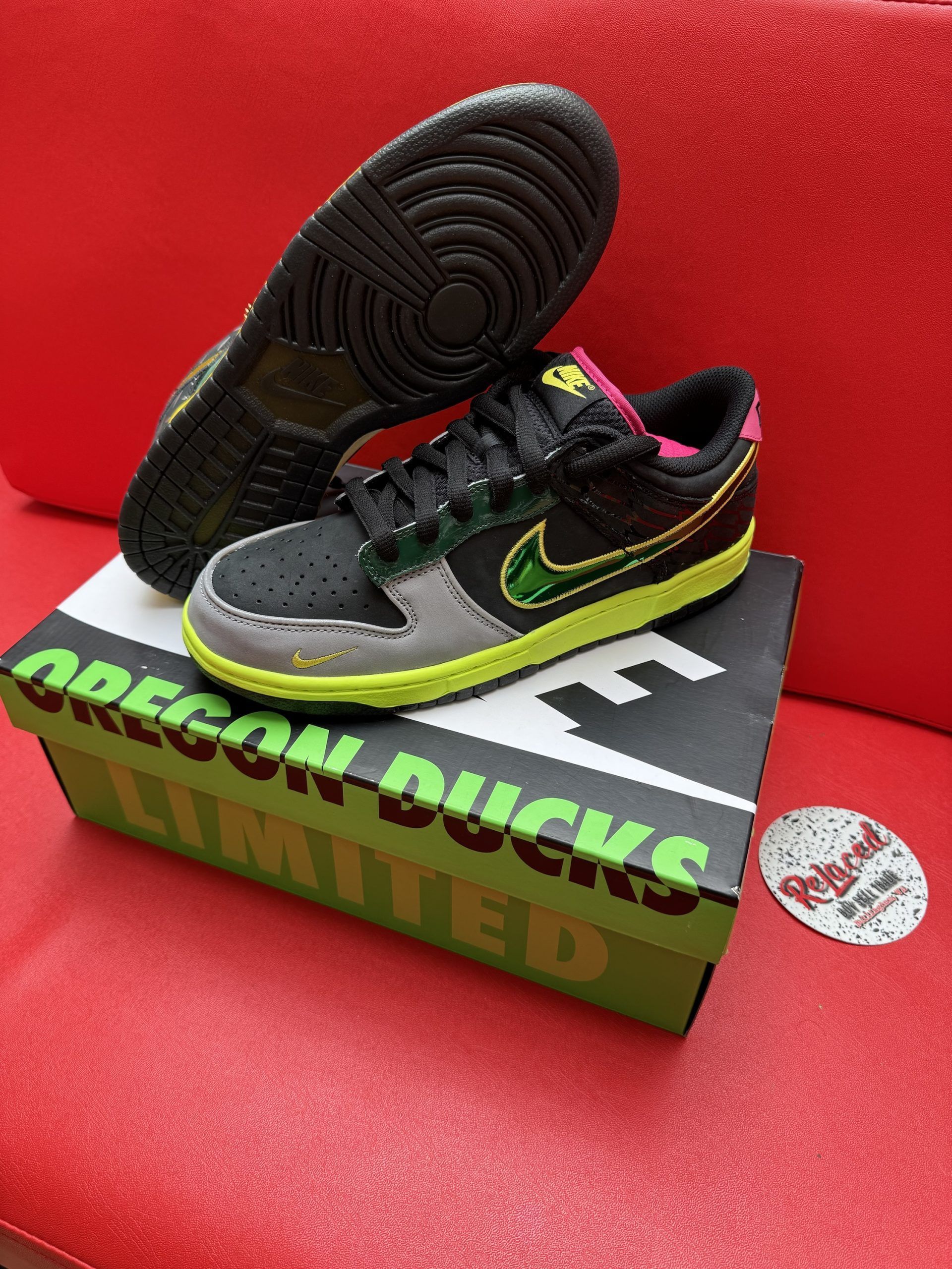 Black, green, and pink Nike Dunk Low Oregon Ducks sneakers on a matching box.