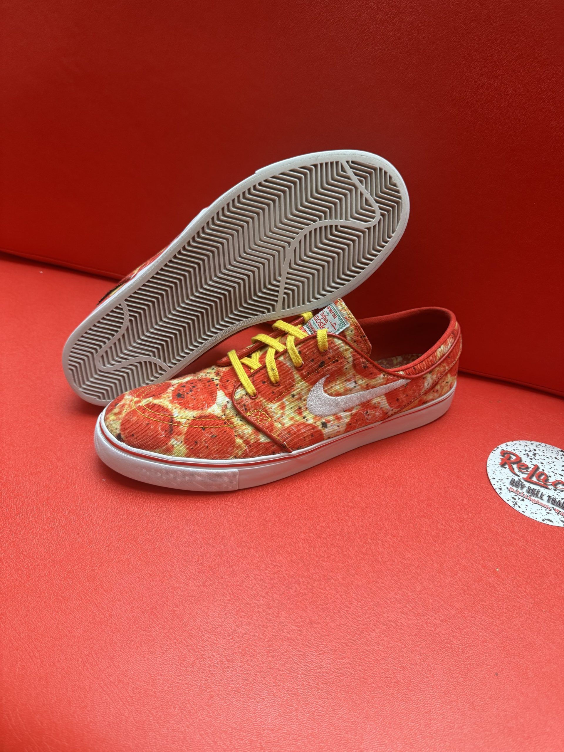 Pizza-themed Nike skate shoes with a red, white, and yellow color scheme, sitting on a red surface.