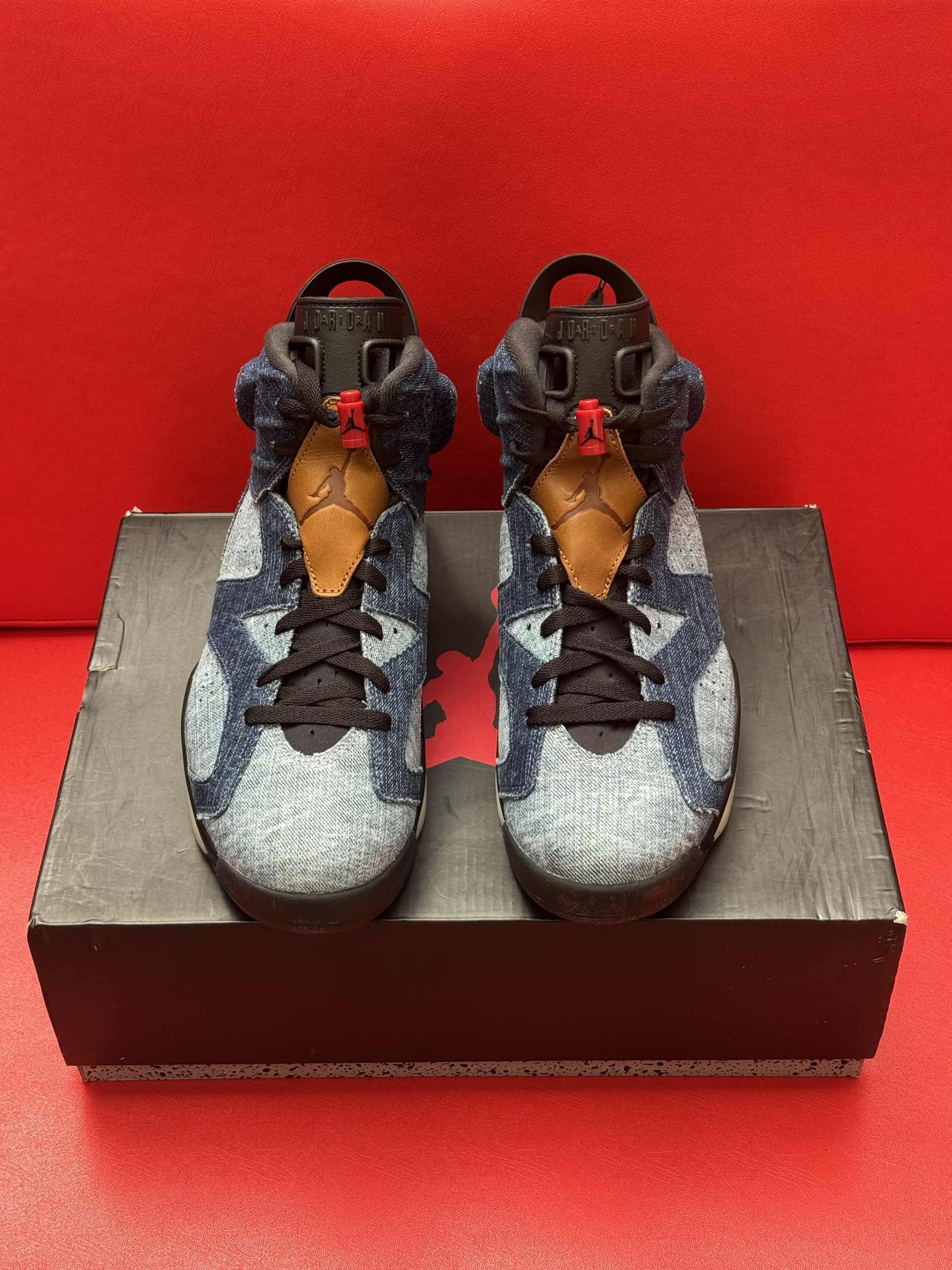 Pair of blue denim Jordan 6 sneakers on top of a black shoebox, with one shoe's sole visible.