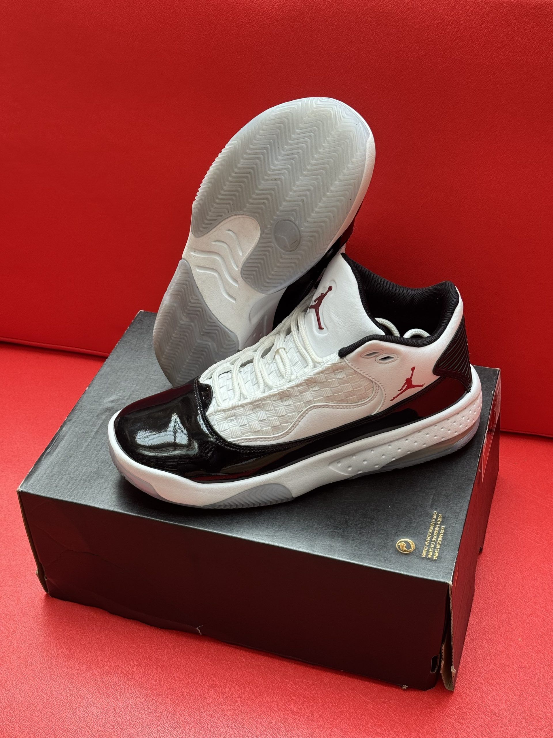 Black and white Air Jordan sneakers on a shoebox against a red background.