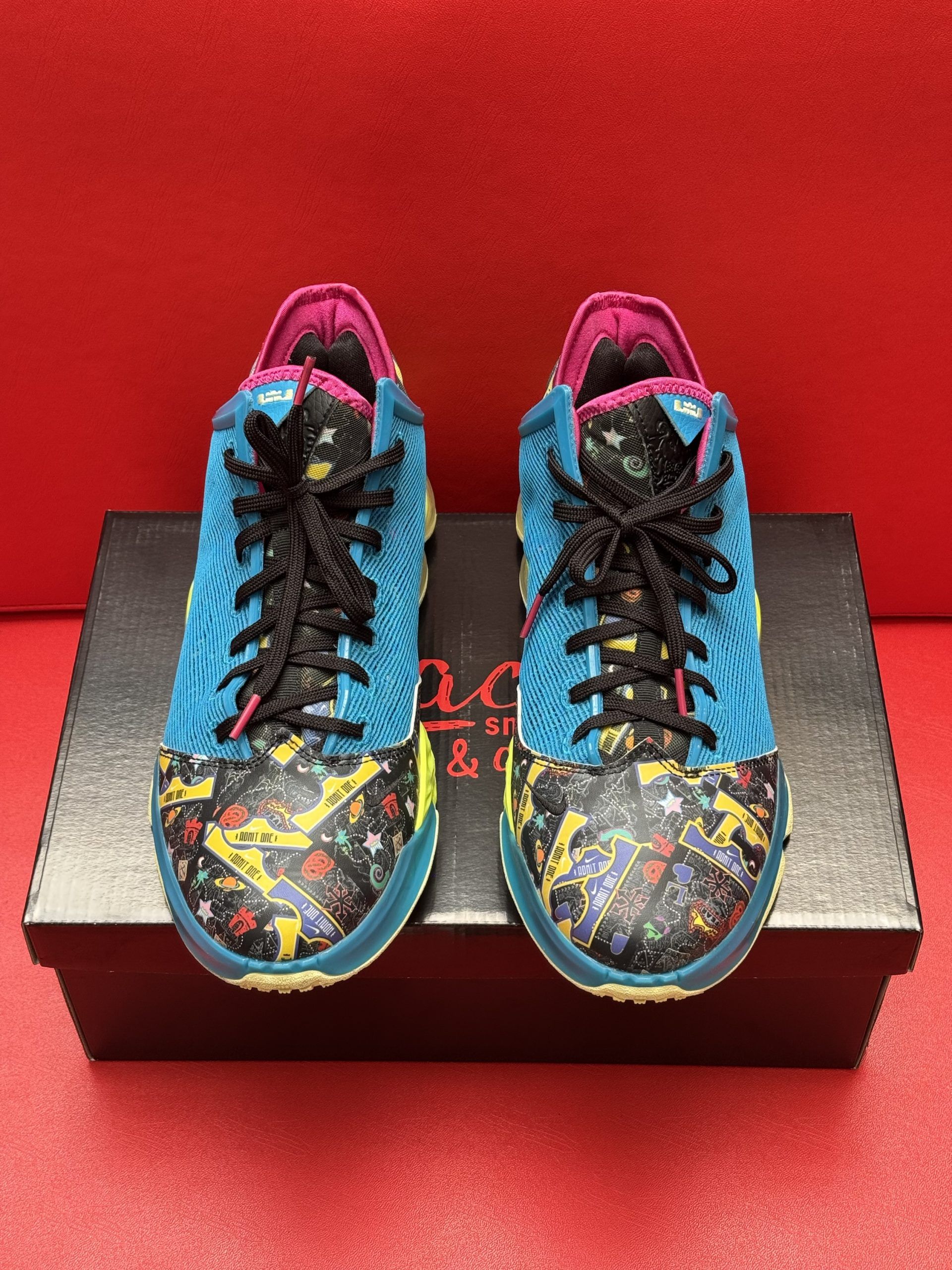 Bright blue and yellow basketball shoe on a black box, sole visible. Interior and heel are pink.