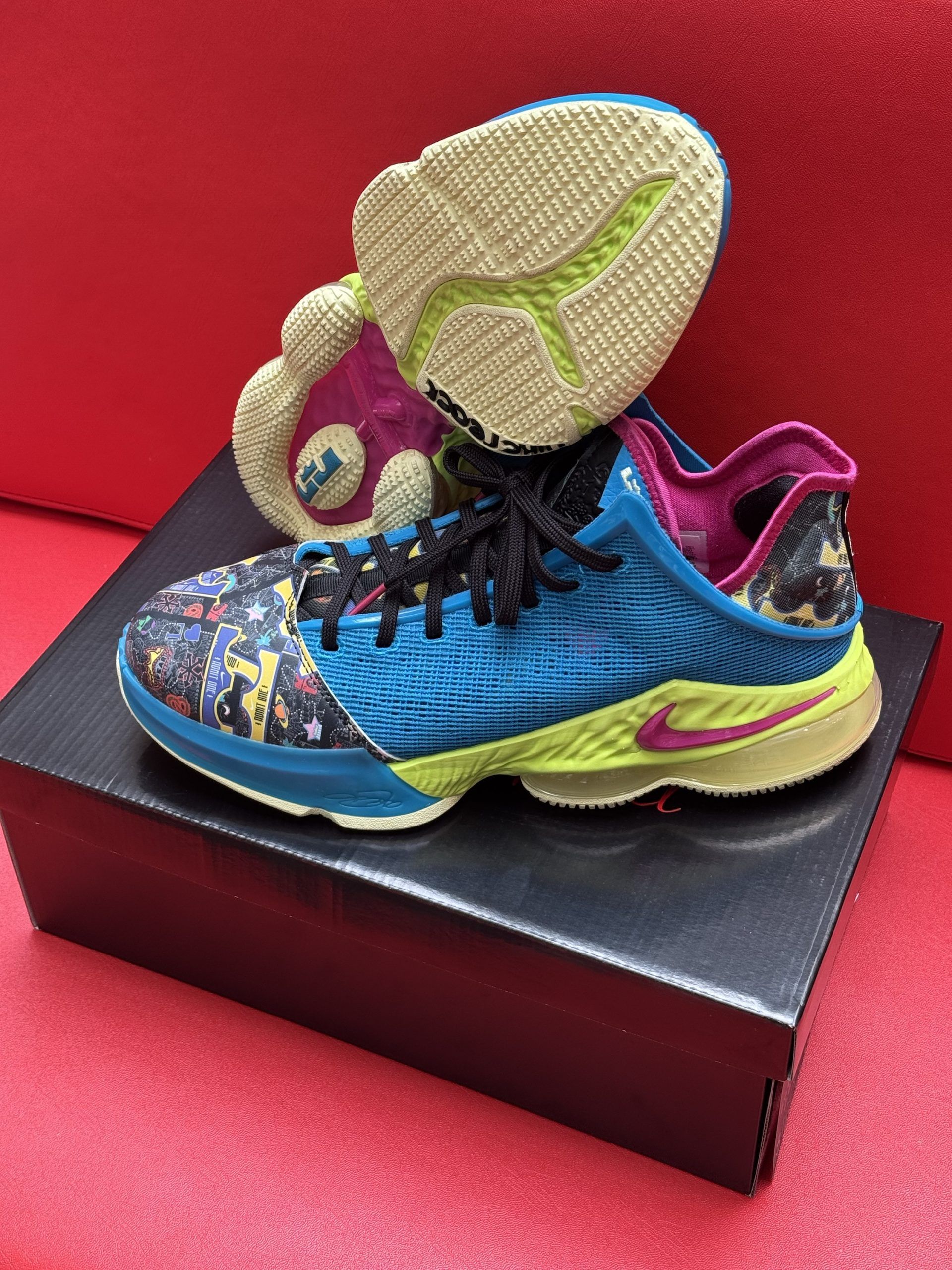 Bright blue and yellow basketball shoe on a black box, sole visible. Interior and heel are pink.