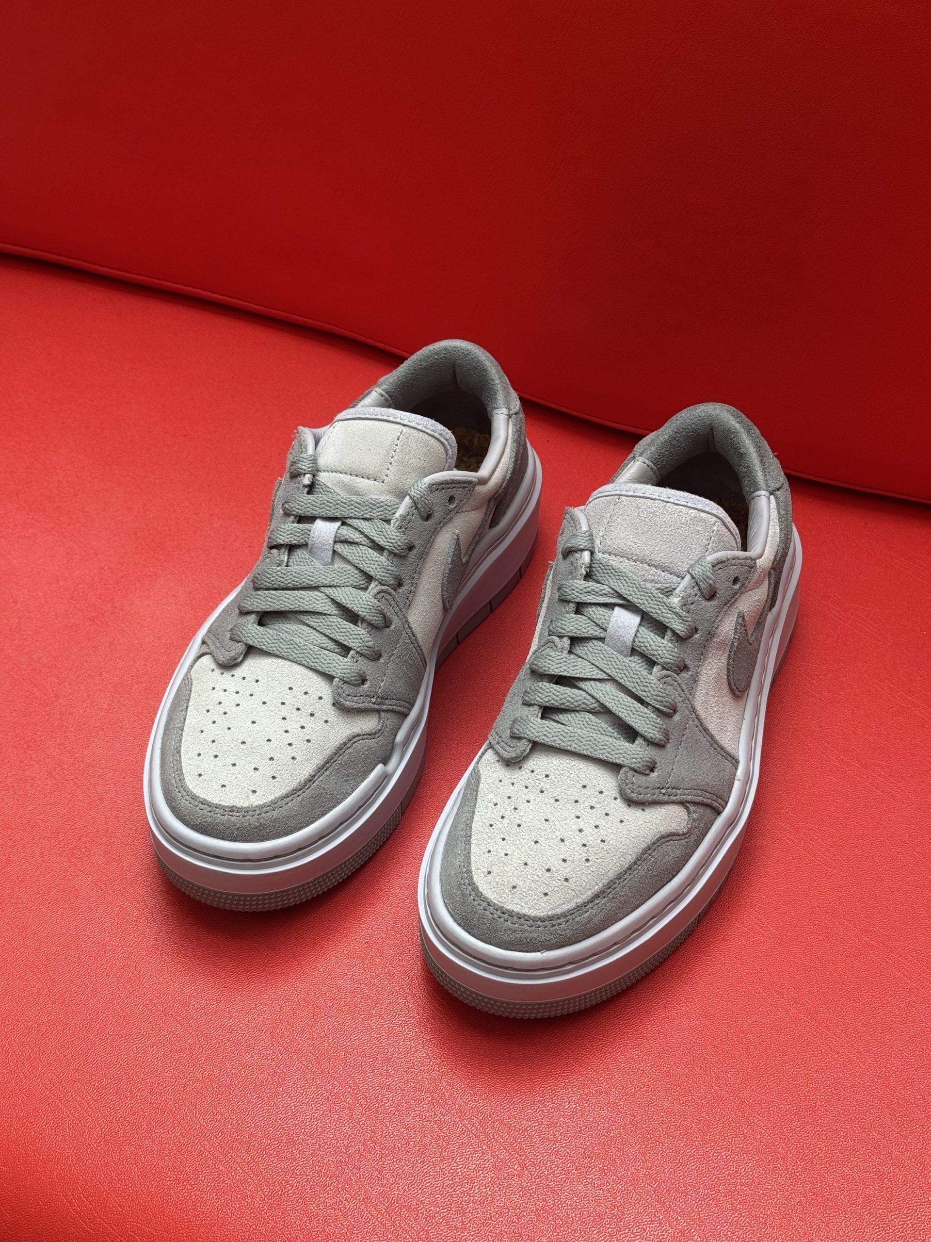 Gray and white Nike sneakers with visible sole, set against a red background.