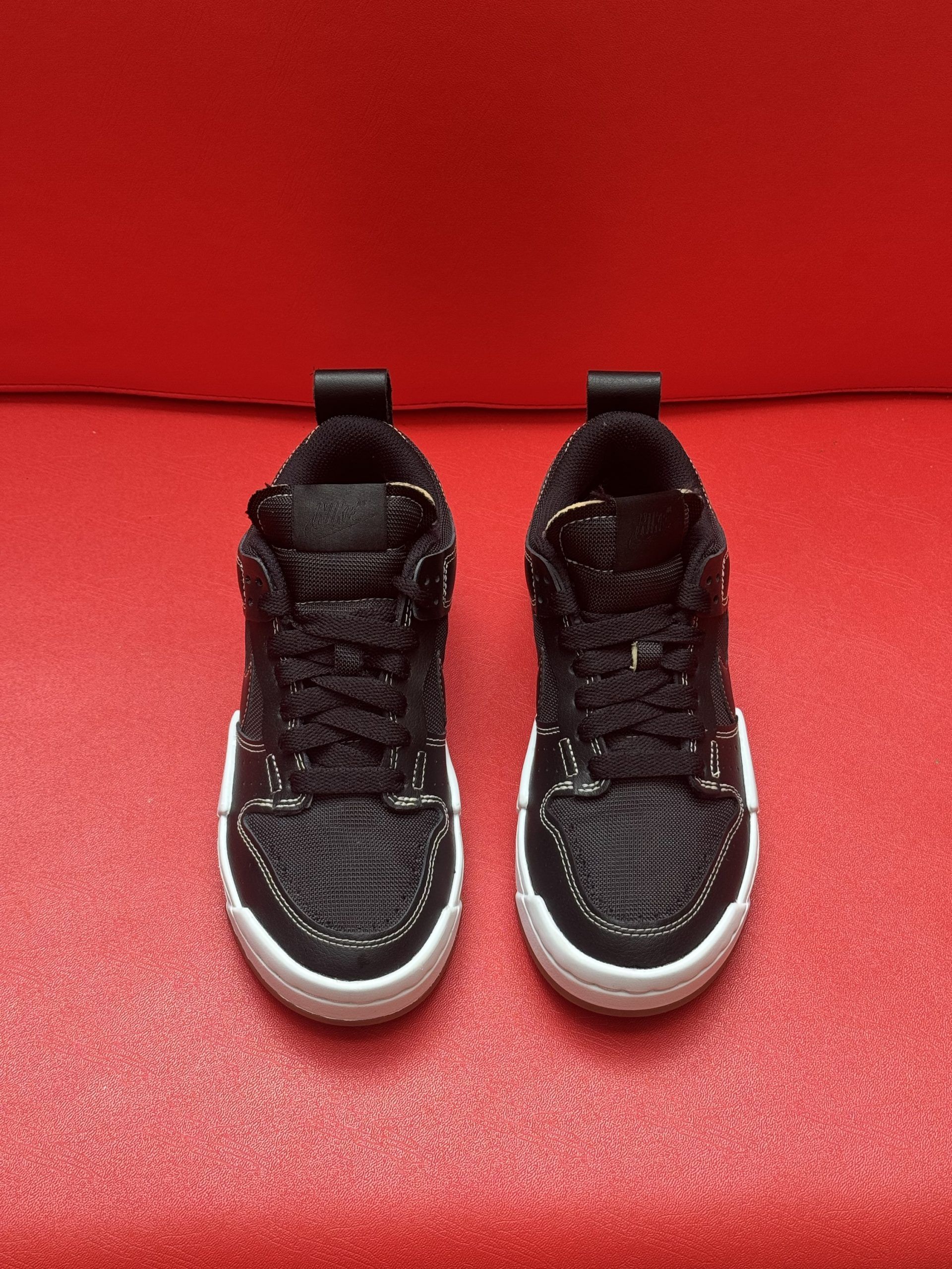 Black and white sneakers with brown sole on red background.