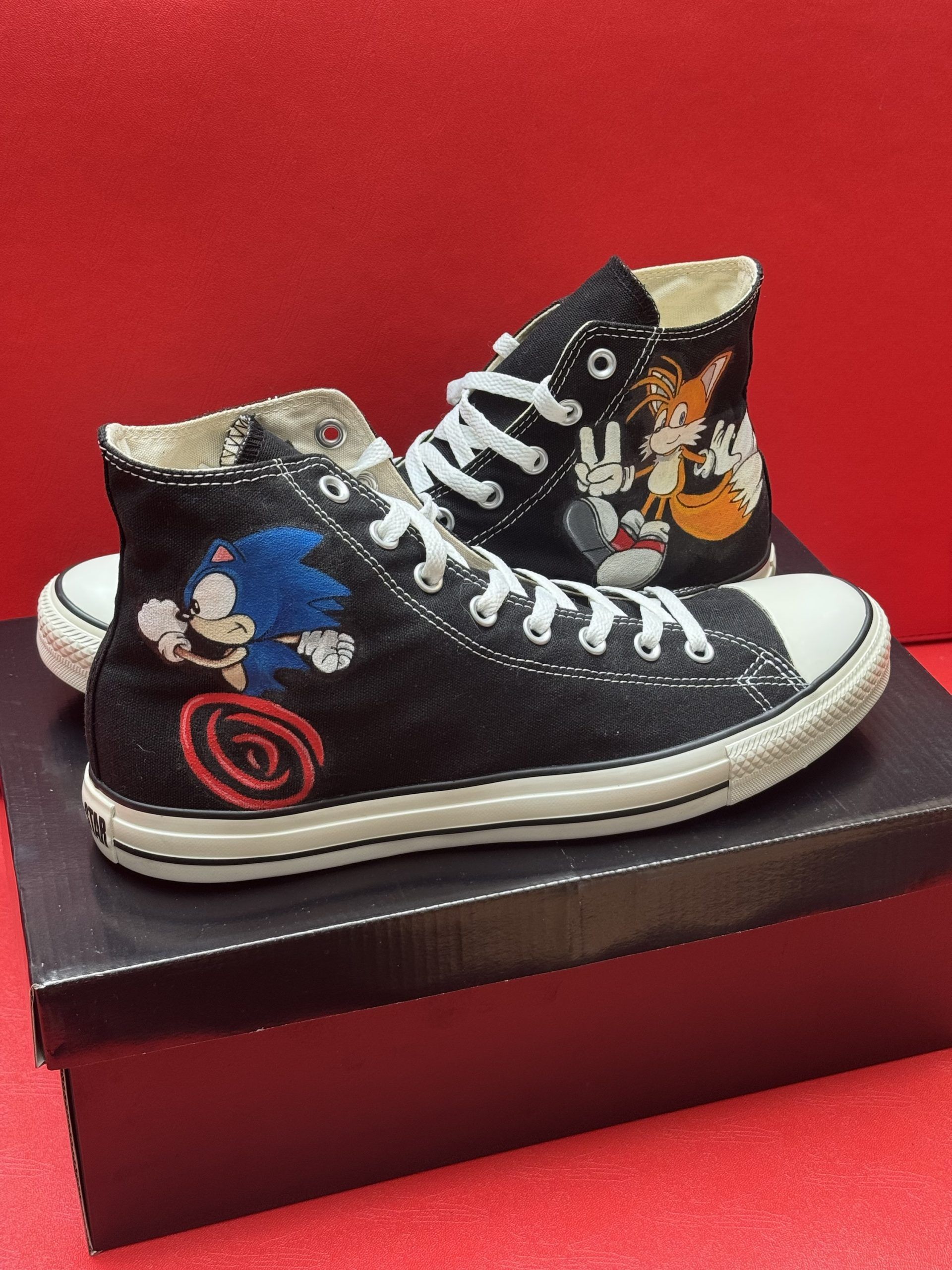 Black high-top sneakers with embroidered Sonic the Hedgehog and Tails characters on a red background.
