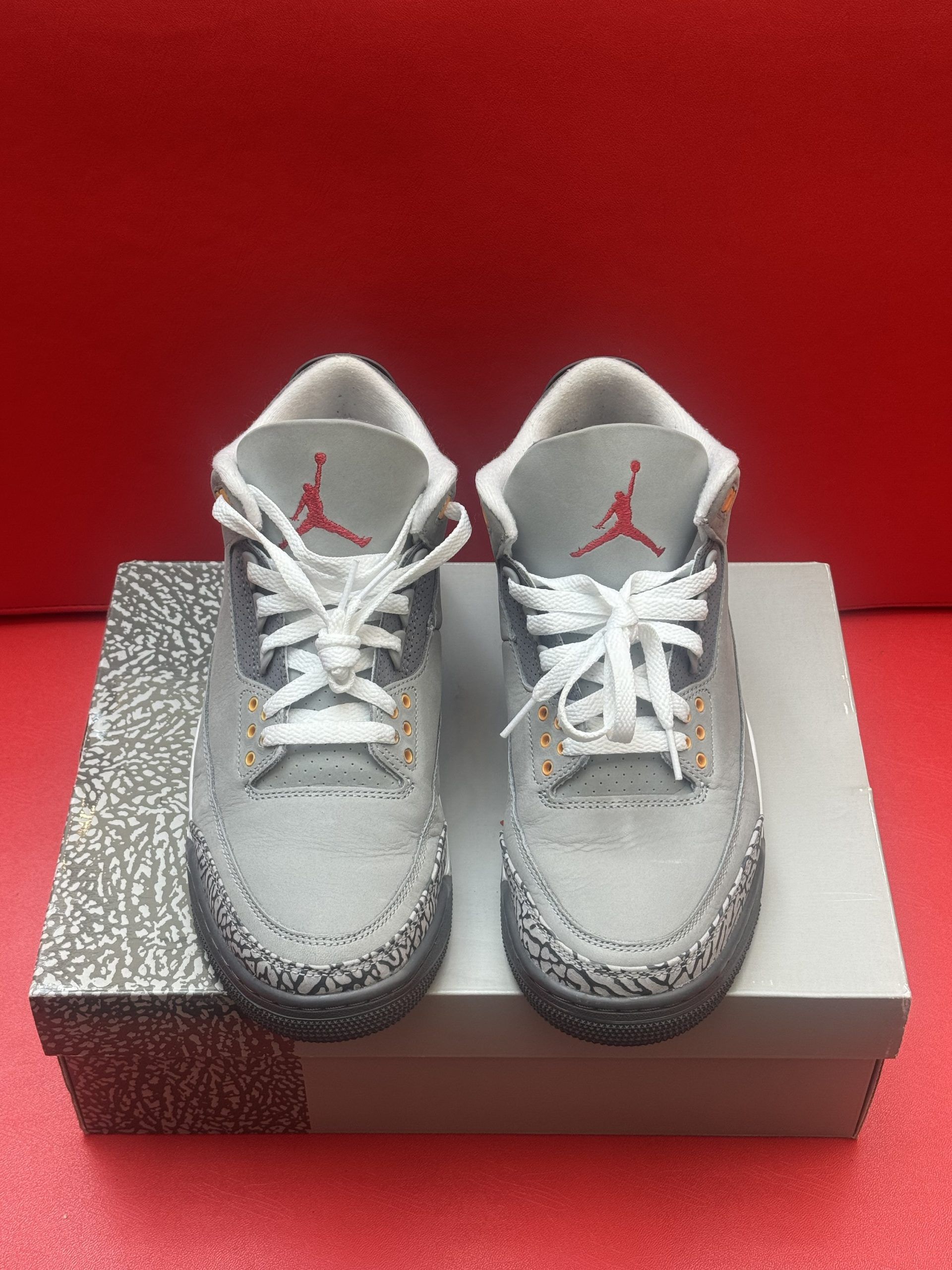 Gray Air Jordan 3 sneakers on a box, with one shoe turned over.