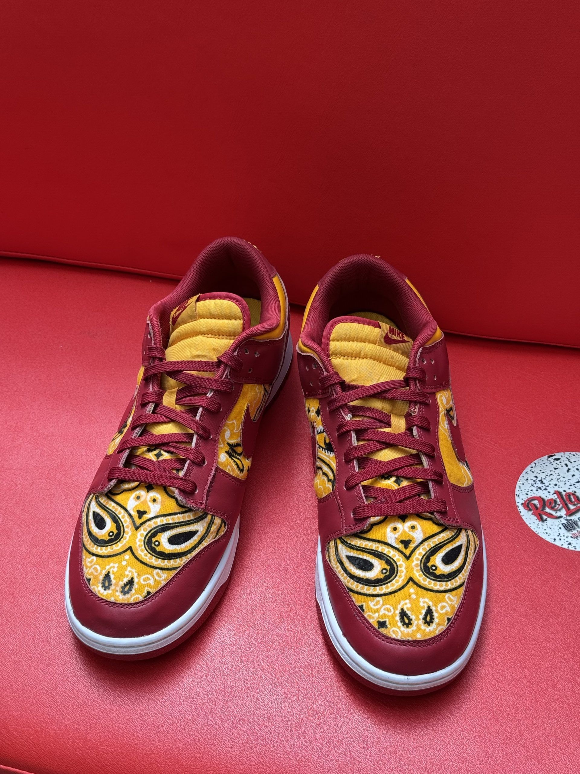 Red and yellow patterned sneakers on a red surface.
