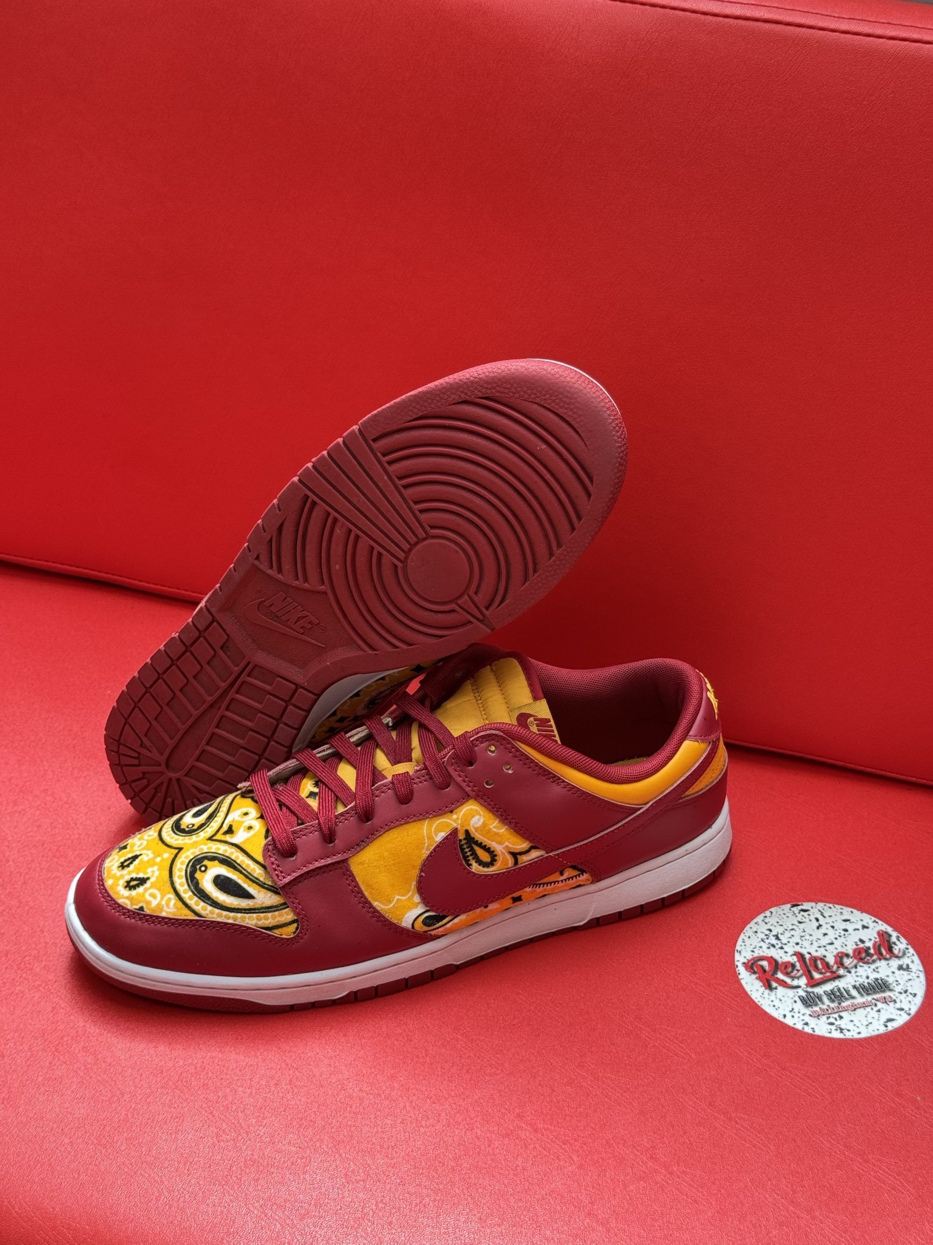 Red and yellow patterned sneakers on a red surface.