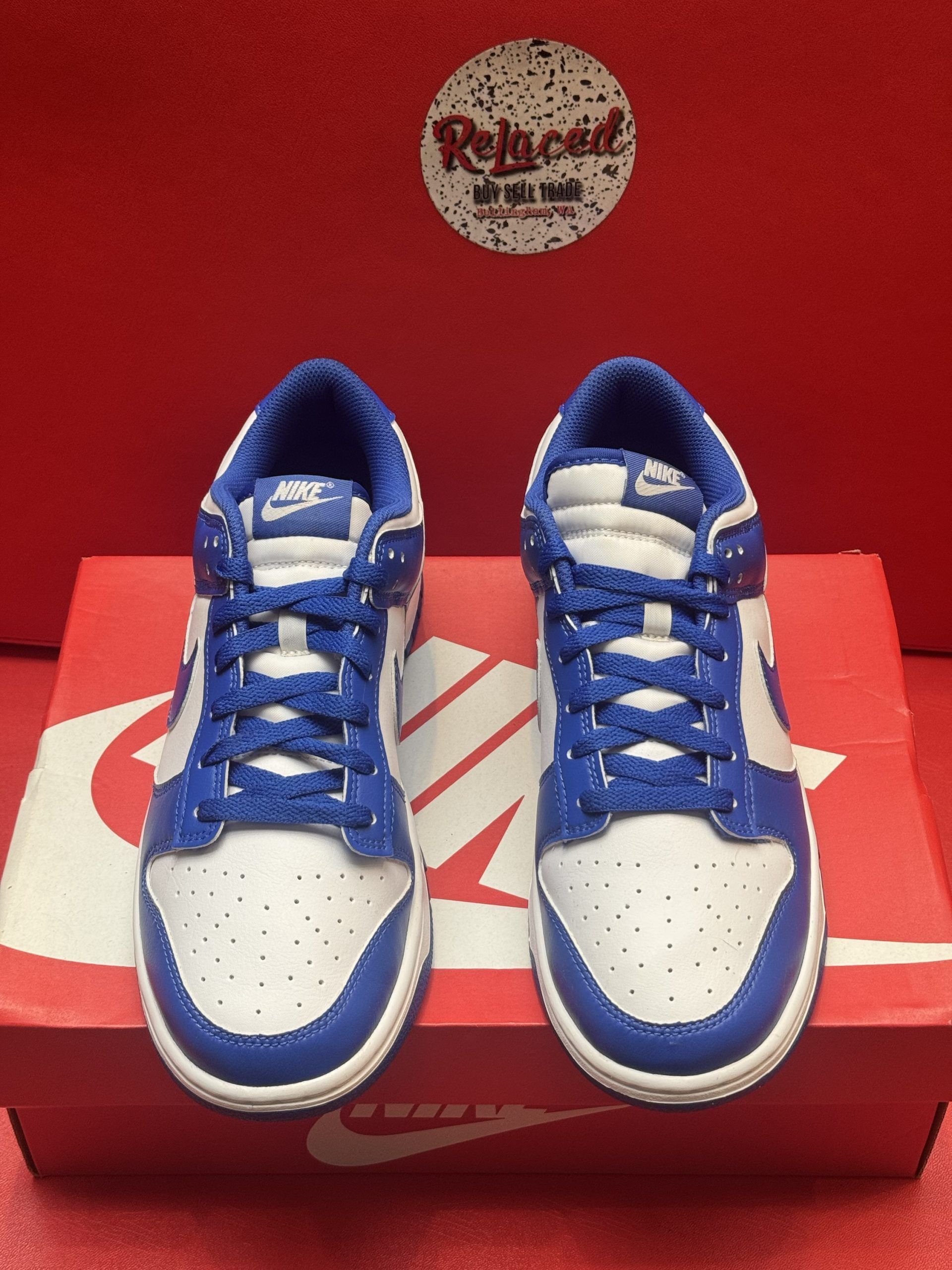 Blue and white Nike Dunk Low sneakers on a red Nike shoebox, with a blue sole visible.