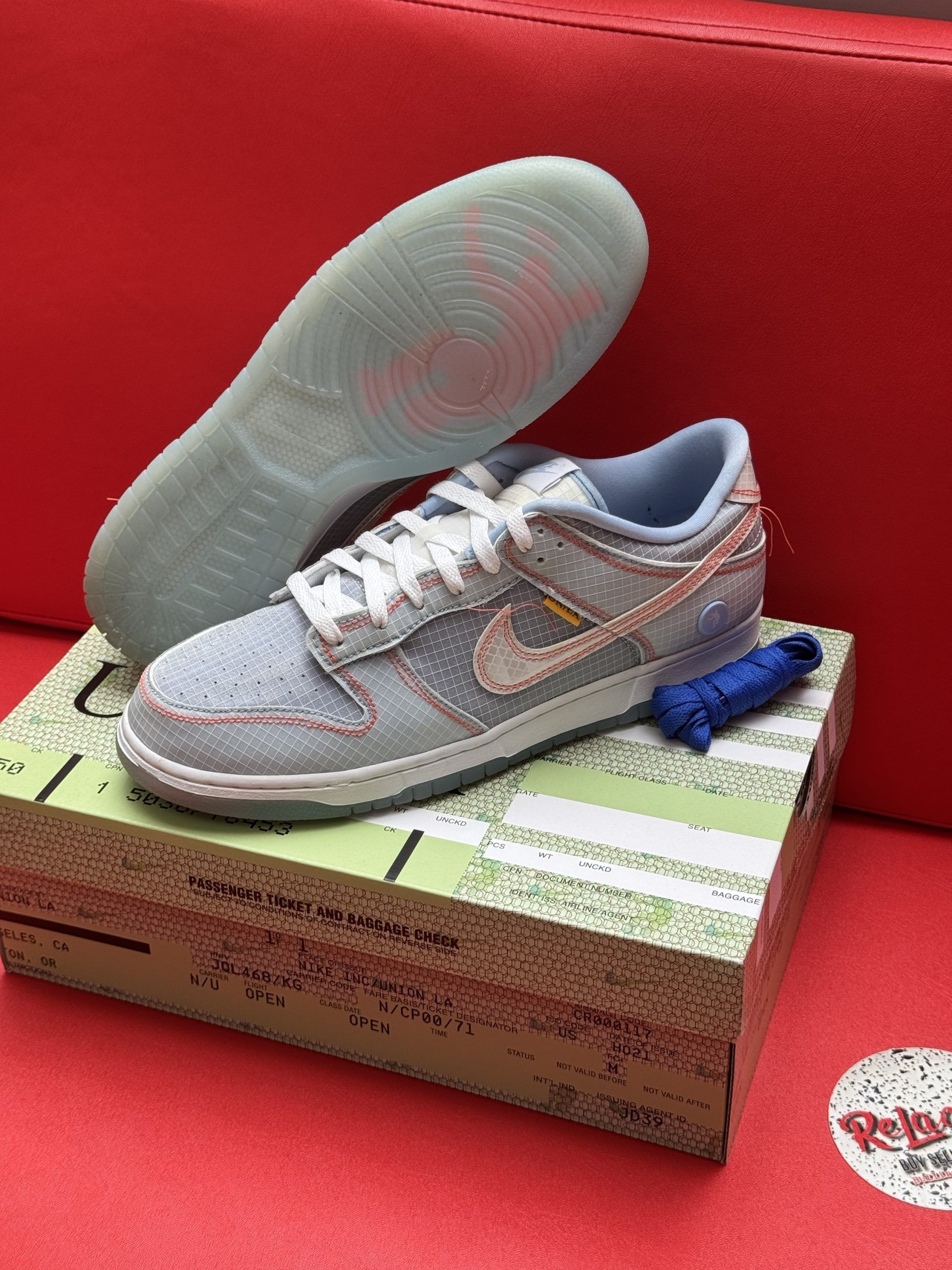 Light blue Nike Dunk Low sneakers with white laces, tan swoosh, on shoe box.