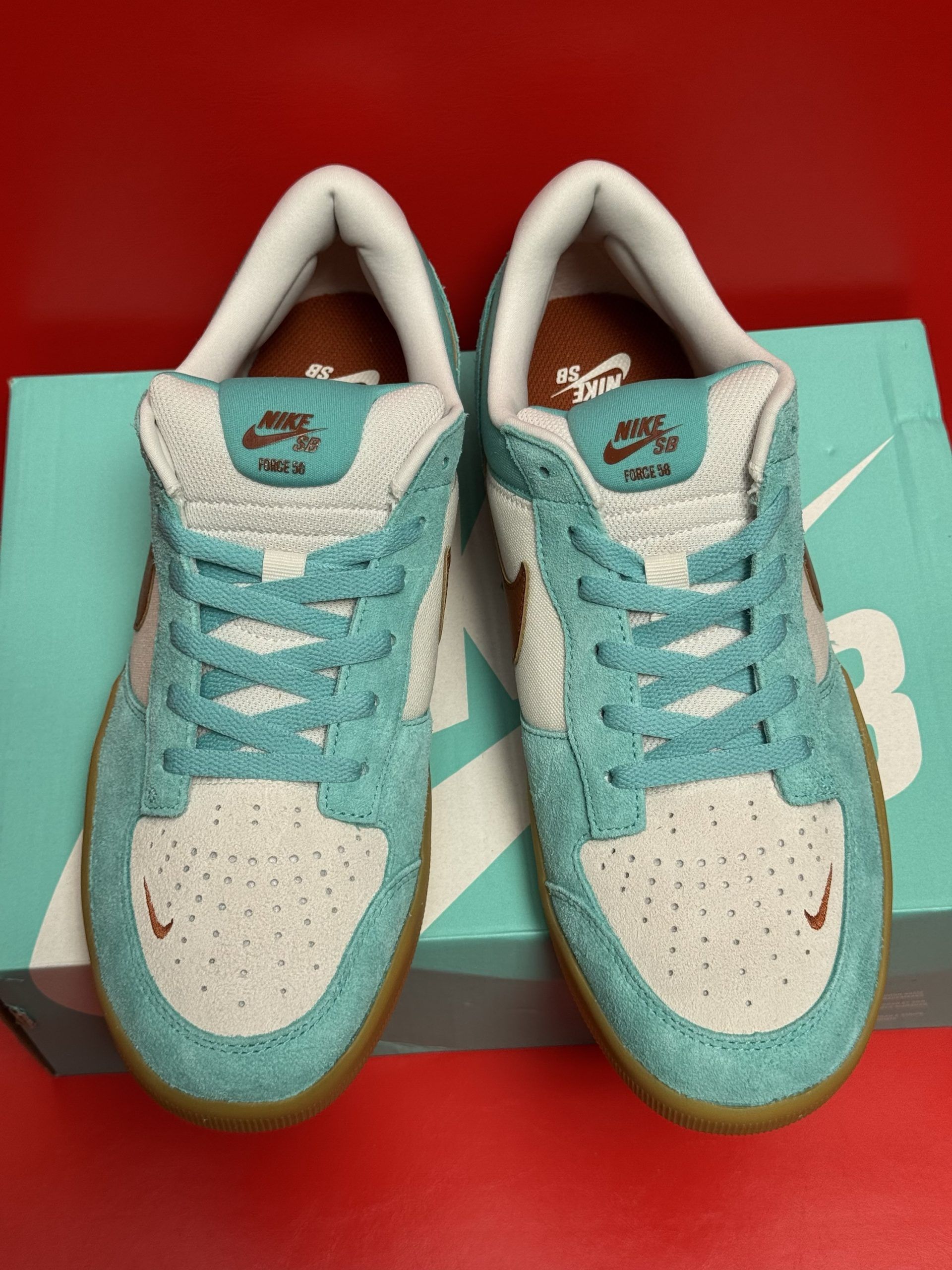 Blue and white Nike SB Dunk Low sneakers with brown accents, resting on a box.