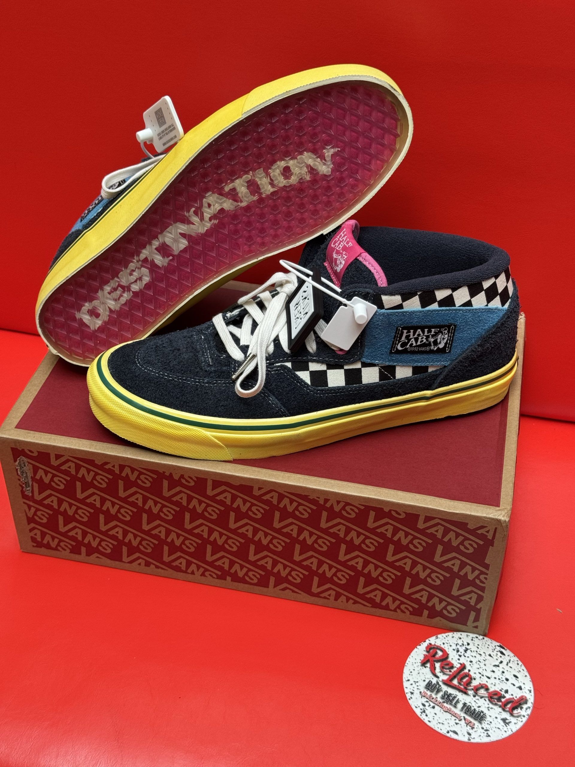 Vans Half Cab sneakers on a box. Blue denim, yellow sole, pink accents. One shoe's insole reads 