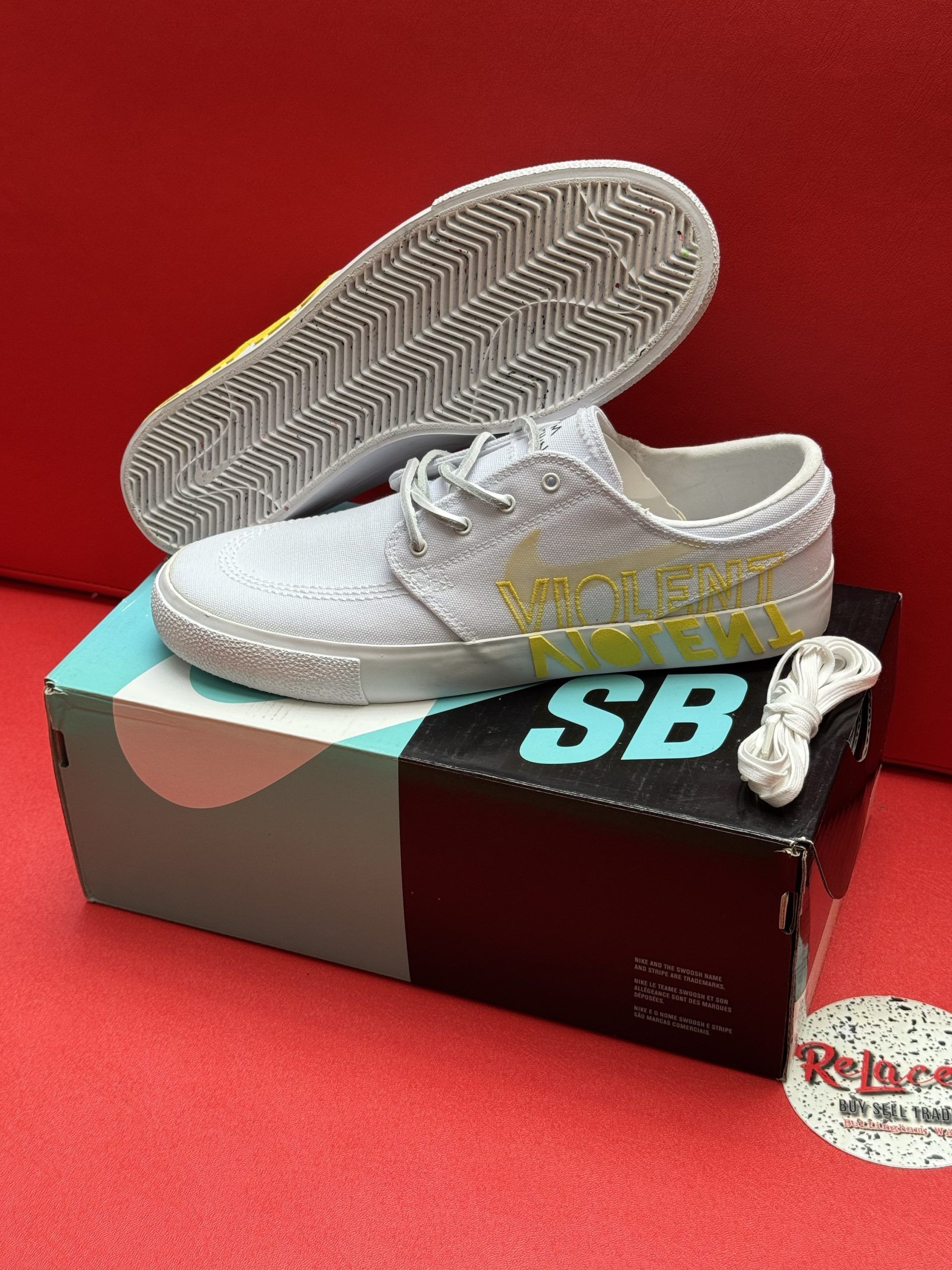 White Nike SB Janoski sneakers with a yellow Swoosh, atop a shoe box.