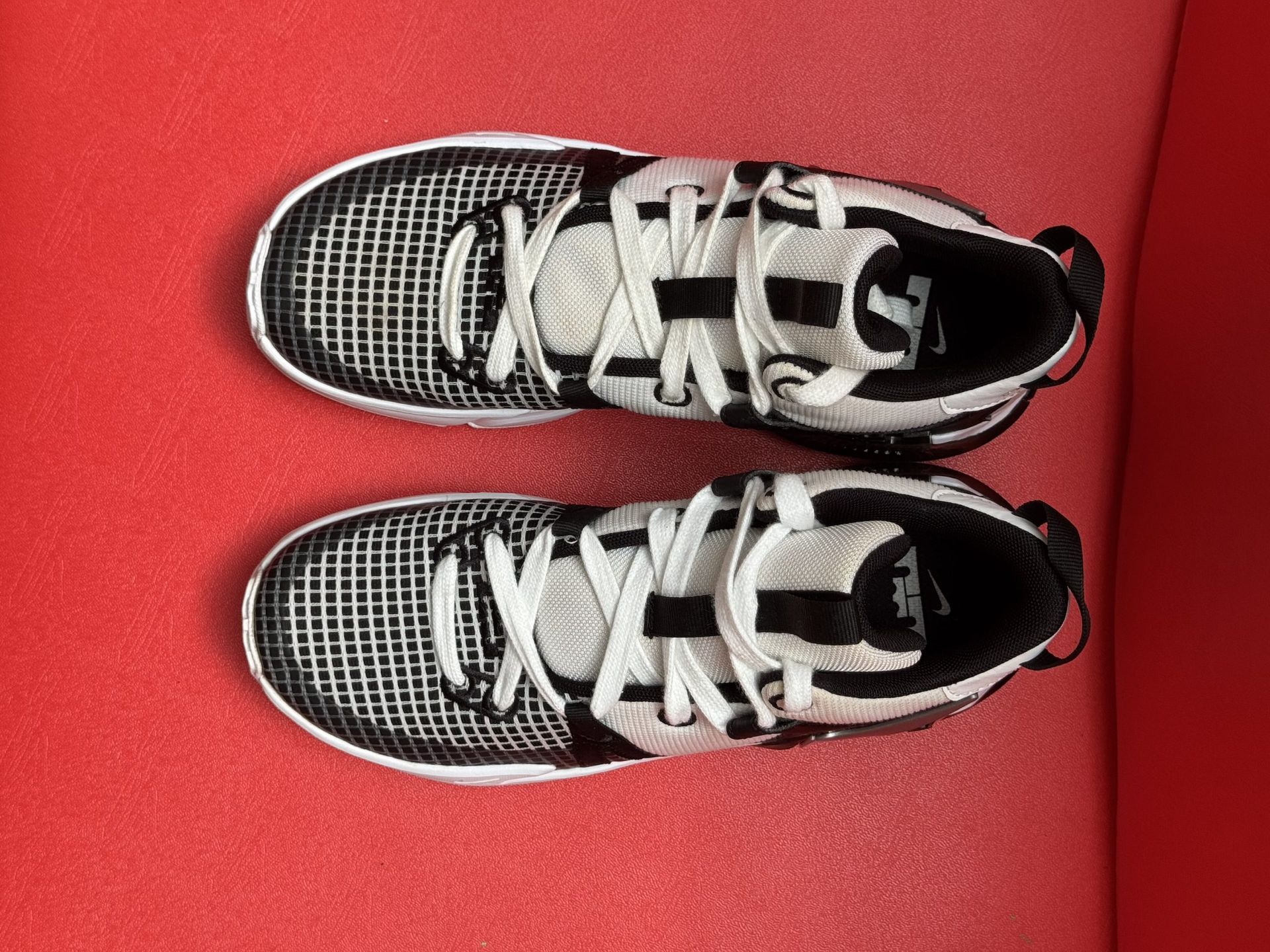 White and black Nike basketball shoe pair on a red surface.