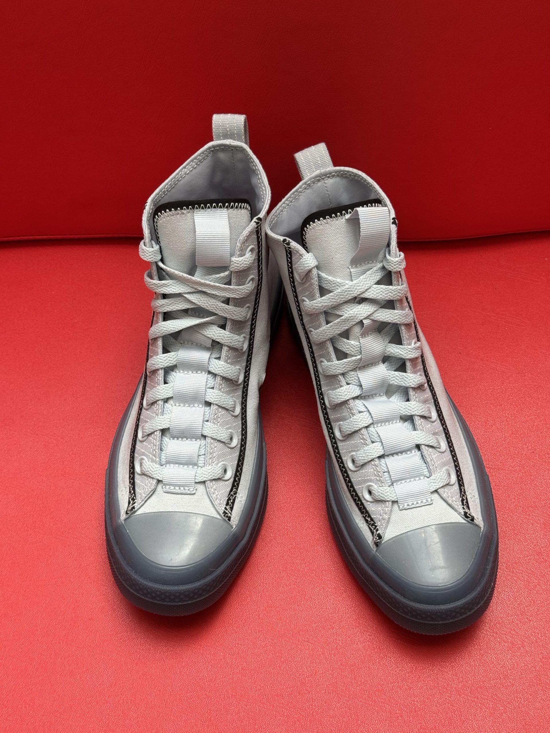 Gray high-top Converse sneakers with black trim on a red surface, sole visible.