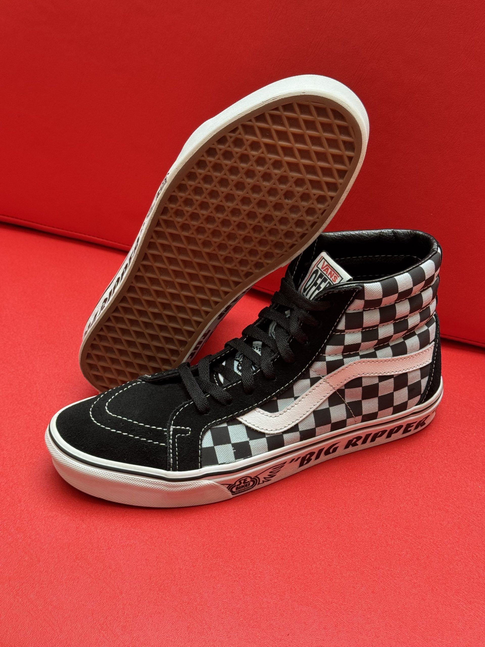 High-top Vans sneakers with black and white checkerboard pattern on a red surface.