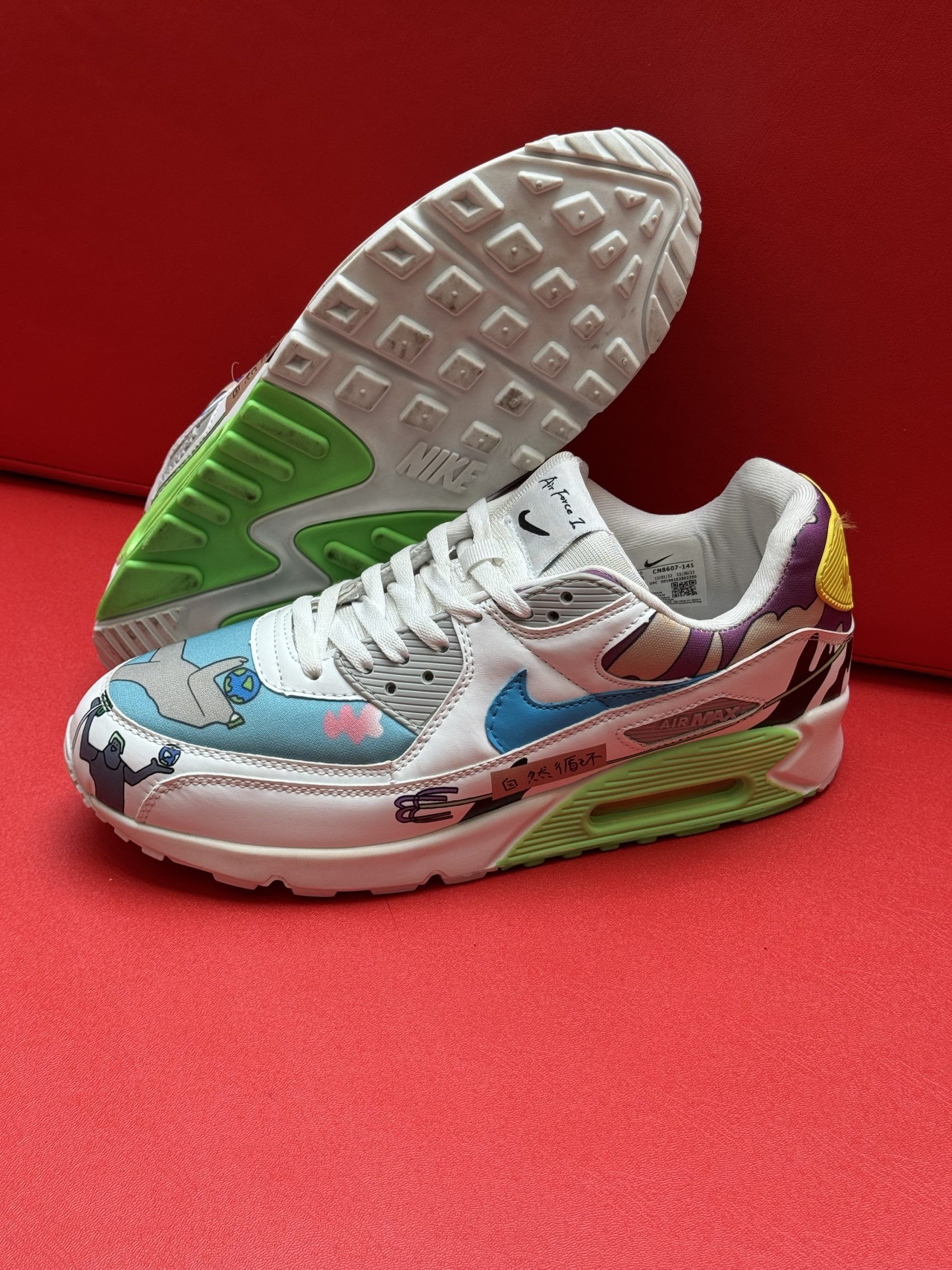 White Nike Air Max 90 sneakers with colorful custom design, red background.