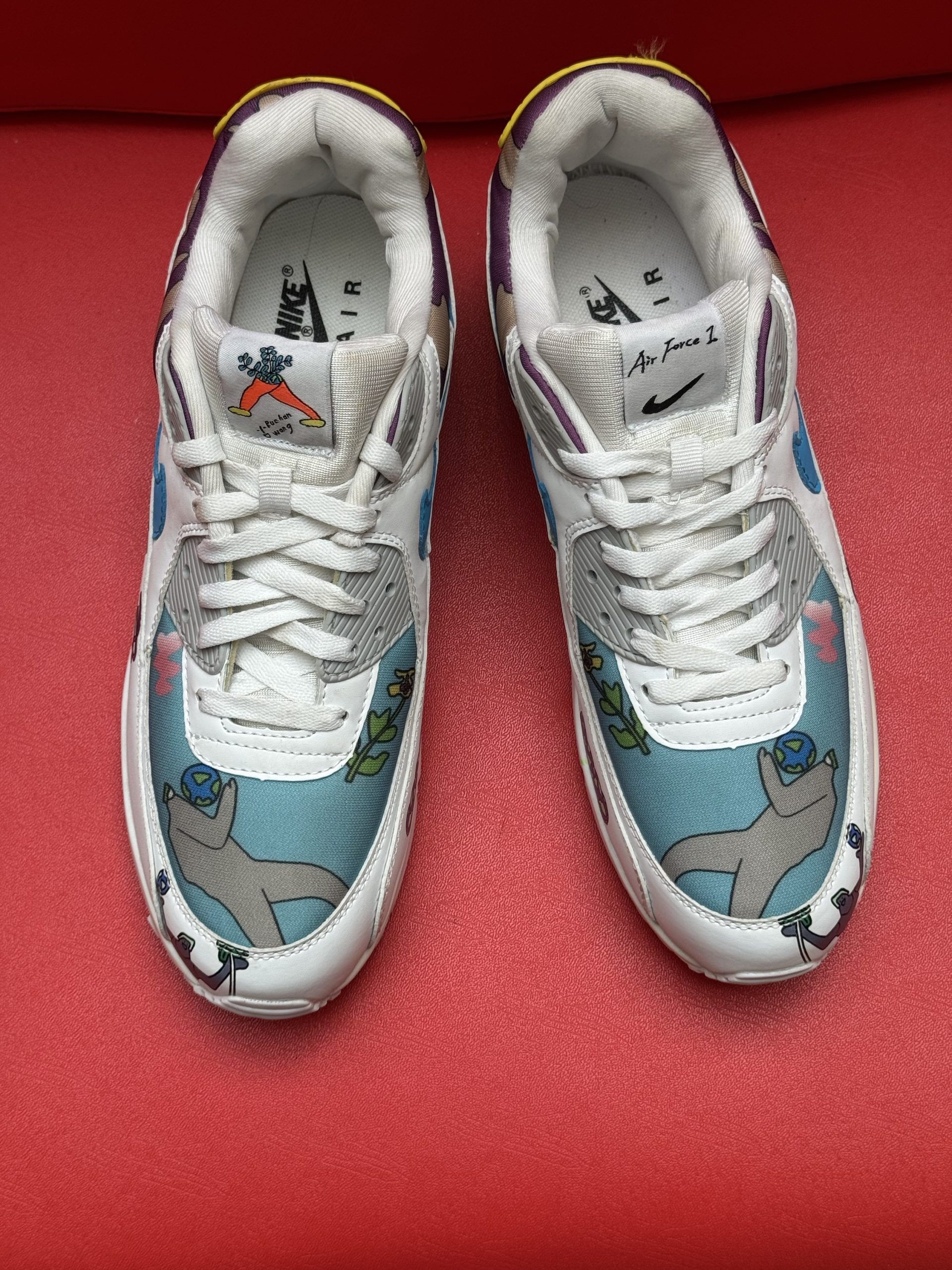 White Nike Air Max 90 sneakers with colorful custom design, red background.