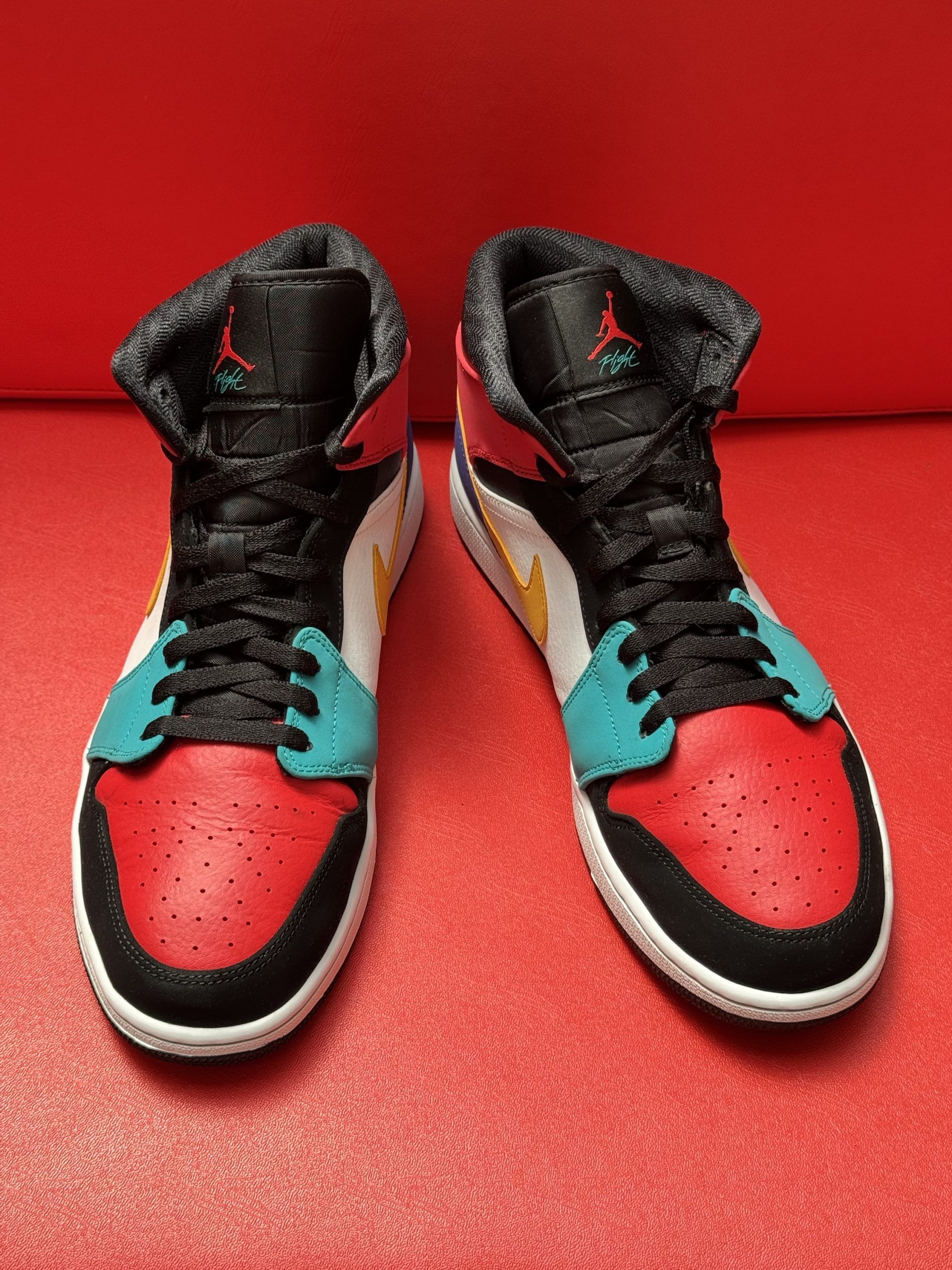 Colorful Air Jordan mid-top sneaker on a red surface, with the sole next to it.