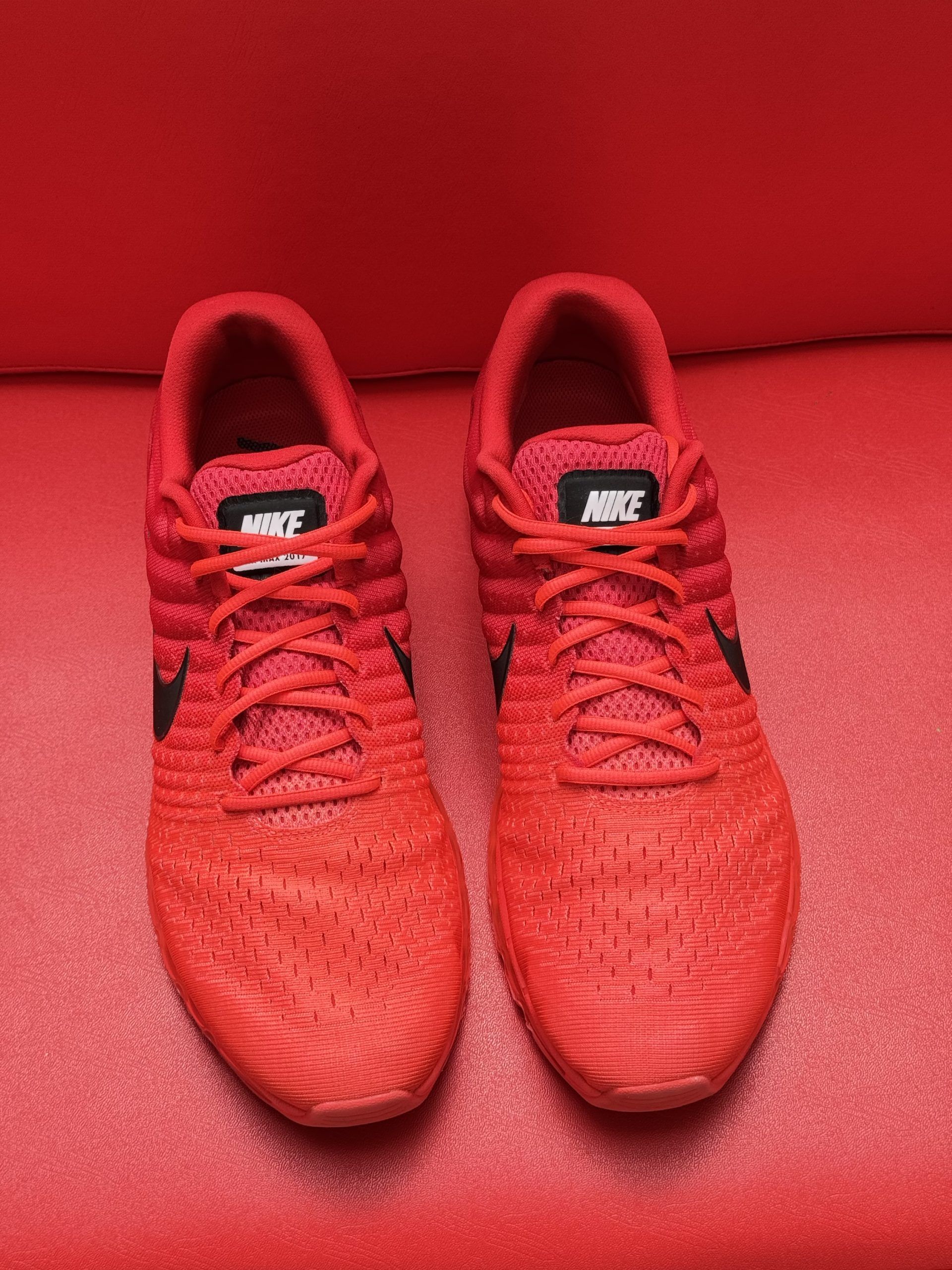Red Nike sneakers on a red surface, with the sole visible.