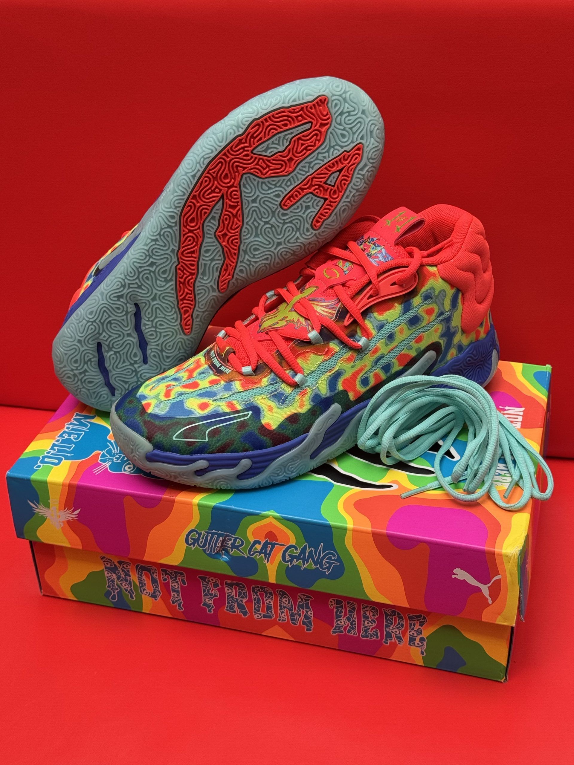 Colorful Puma sneakers with a matching box on a red background.